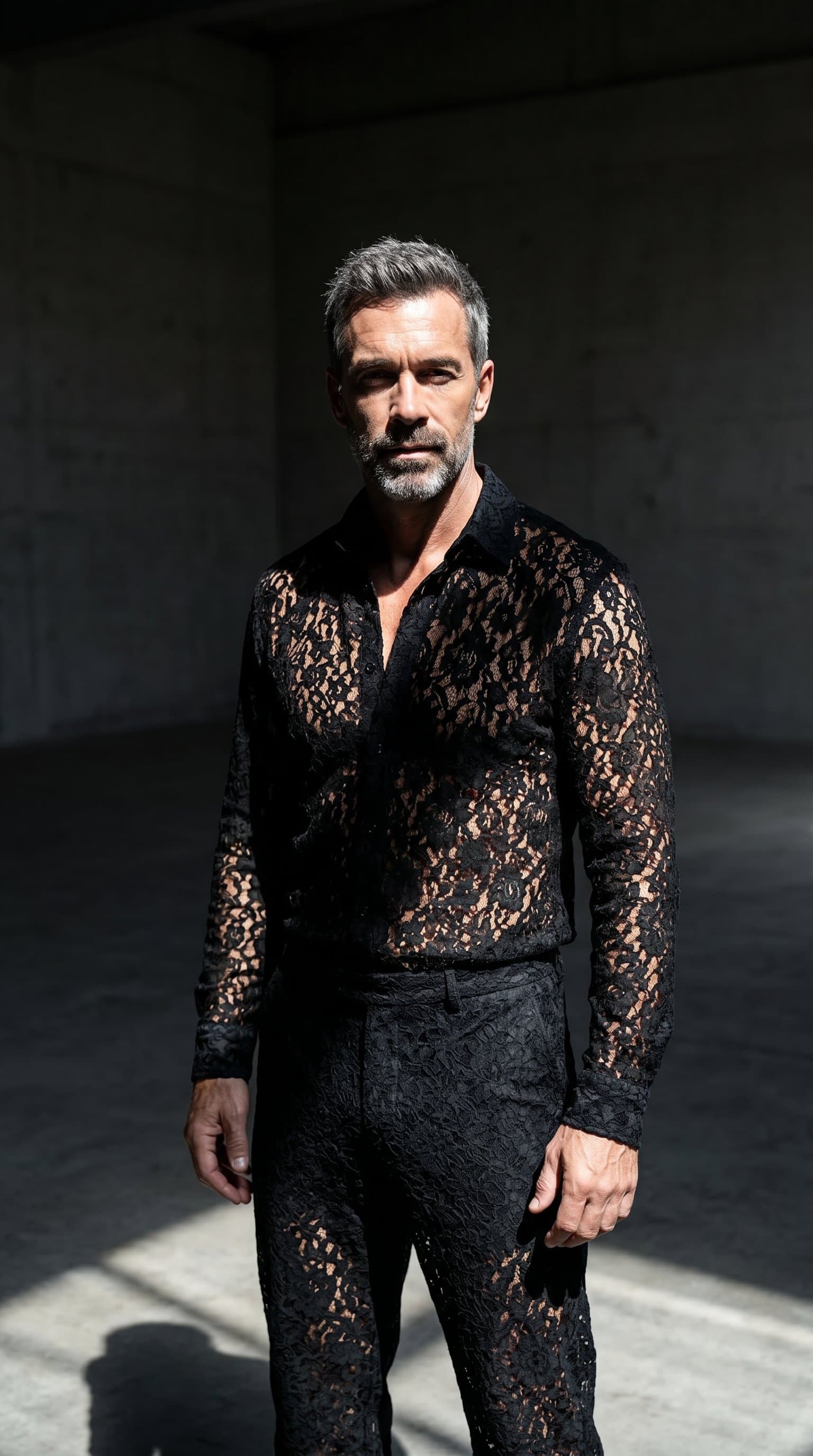man in an empty room, dressed in a lacy outfit and lit by a single light source casting dramatic shadows