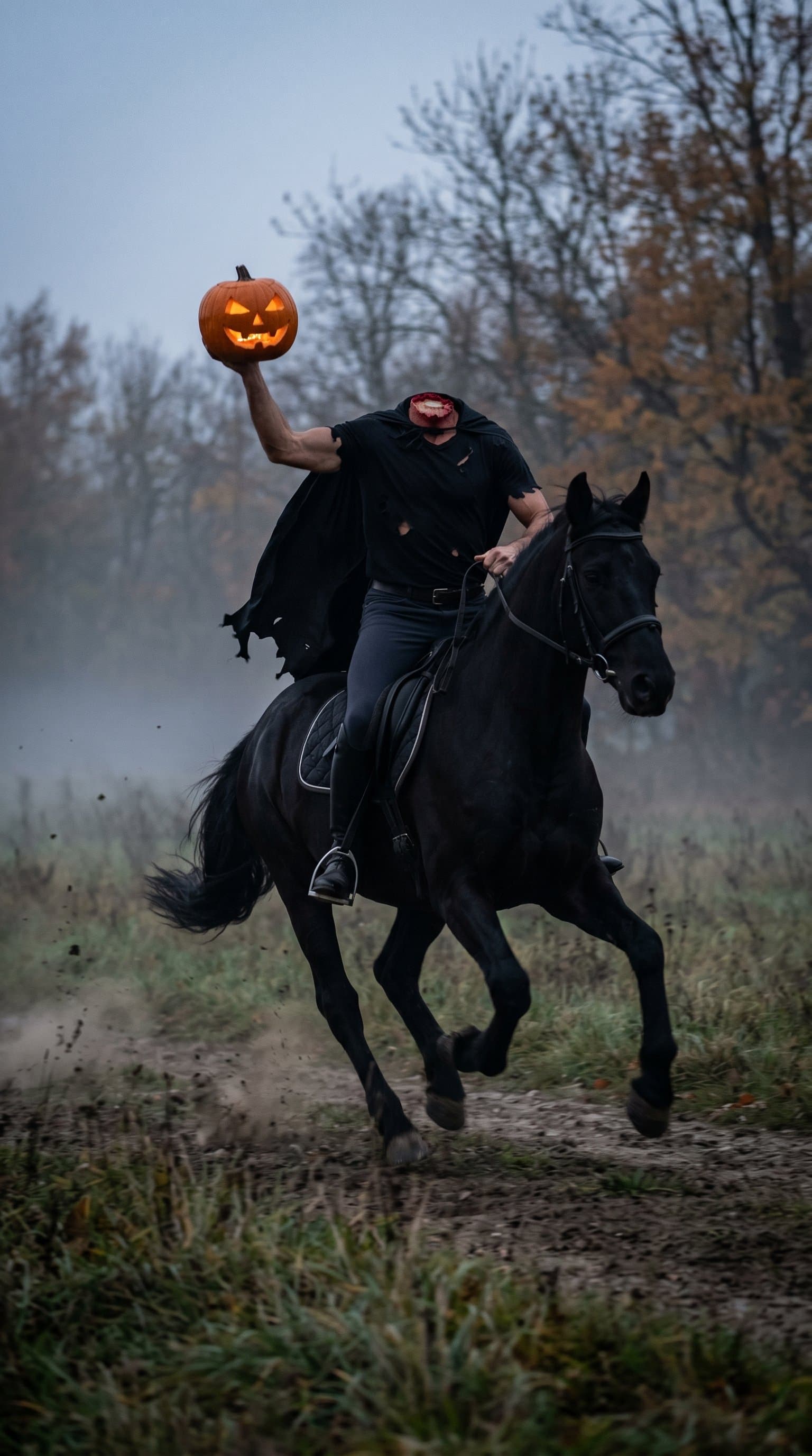 A man in a headless horseman costume, galloping through a foggy field with a pumpkin held aloft