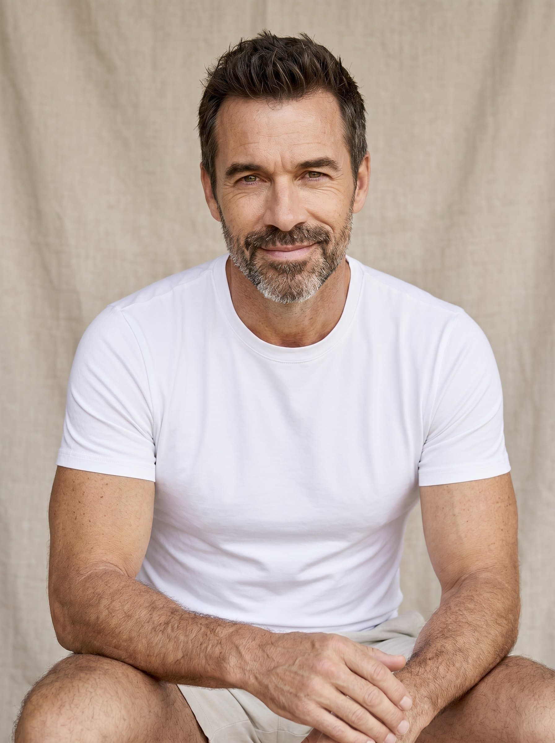 is captured with a gentle smile, a neutral backdrop of textured fabric accentuating their warm presence. Their considerate expression suggests a deep capacity for listening.