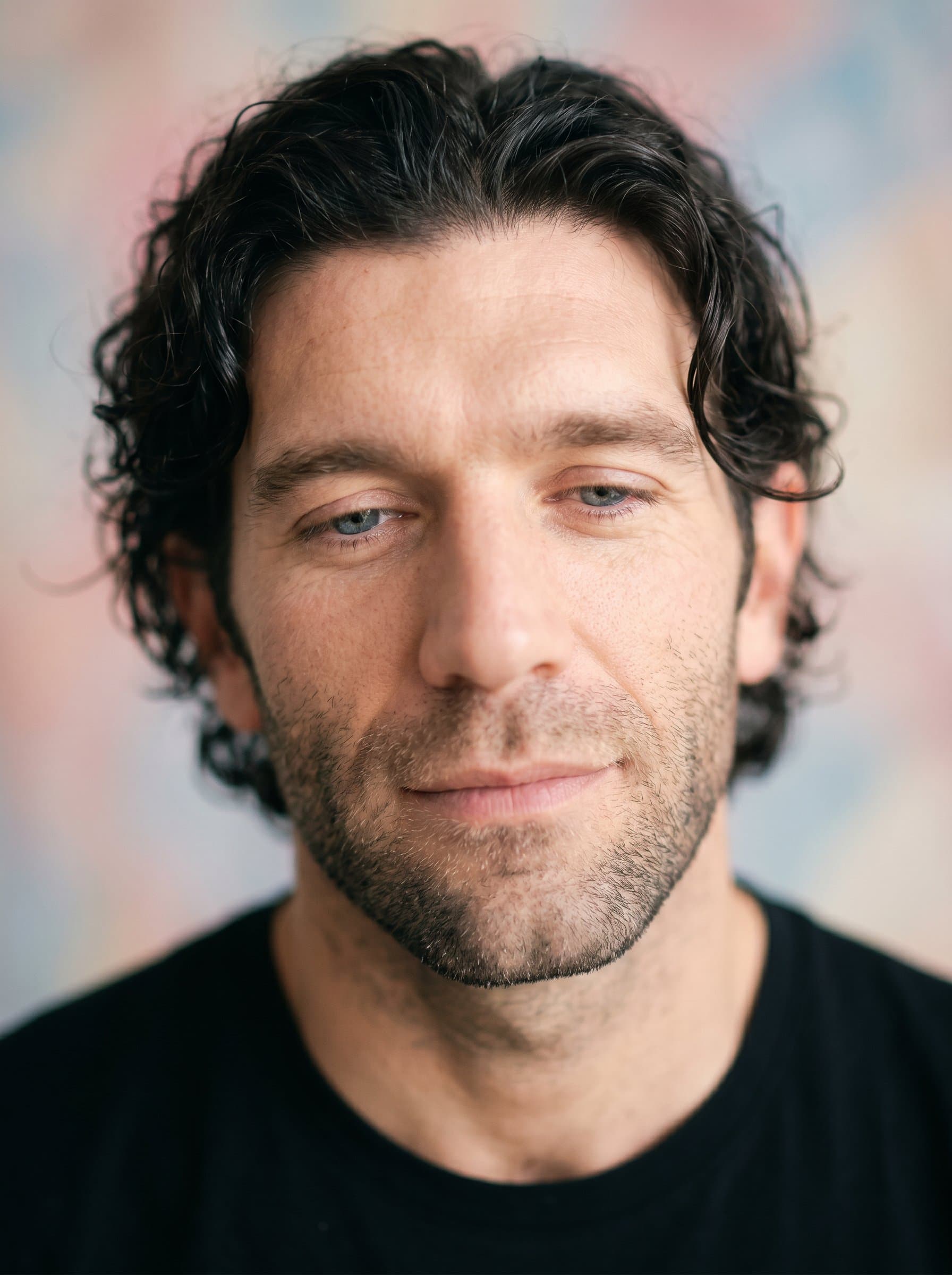 Produce a focusing on the actor's serene and calm nature. Apply soft focus techniques with pastel backgrounds, ensuring a gentle yet clear capture of facial details that convey peace and introspection.