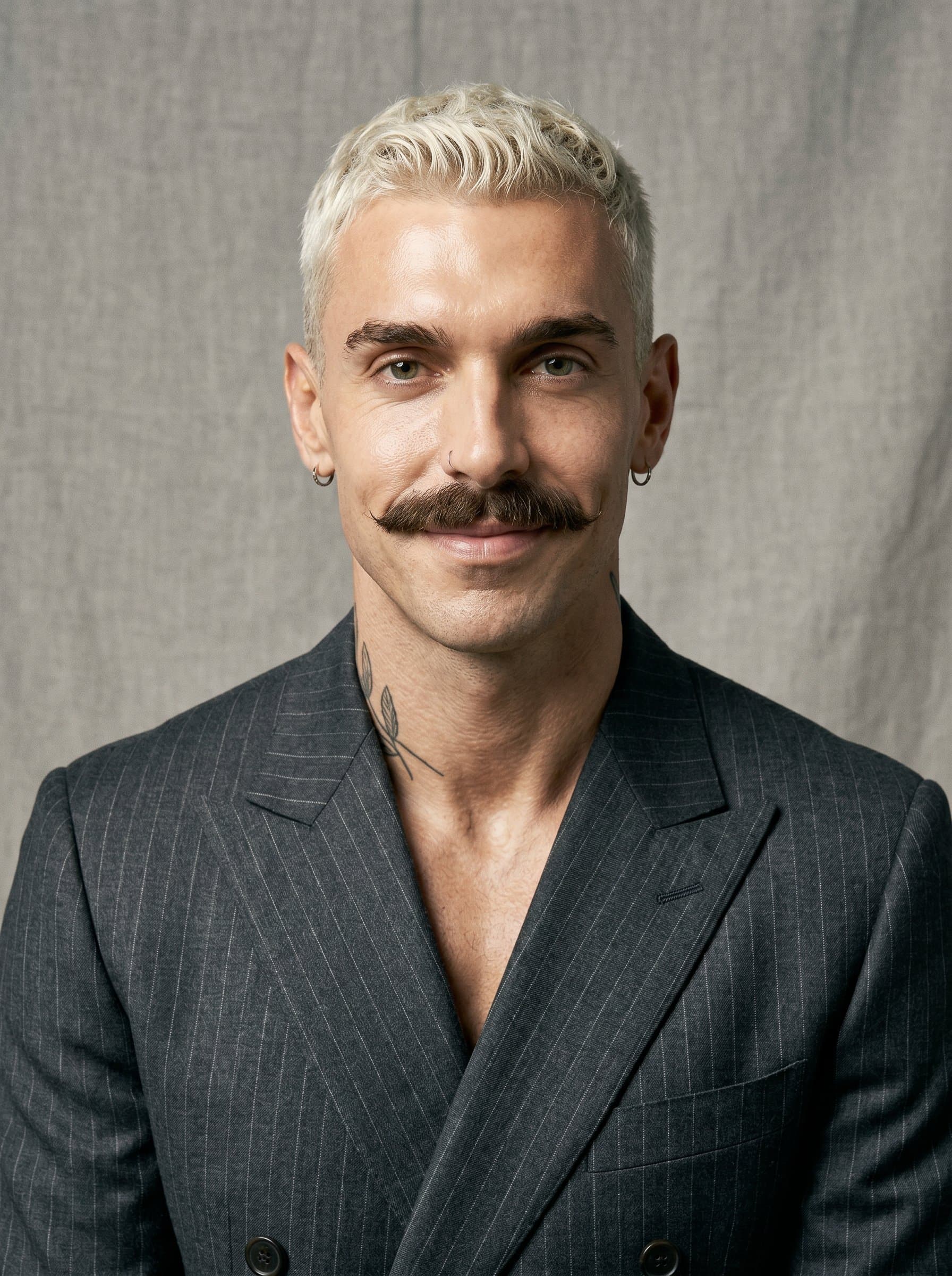 : Design an AI headshot showcasing an attorney wearing a subtle pinstripe suit, against a textured fabric backdrop, portraying elegance and sophistication, alongside a poised yet inviting expression.