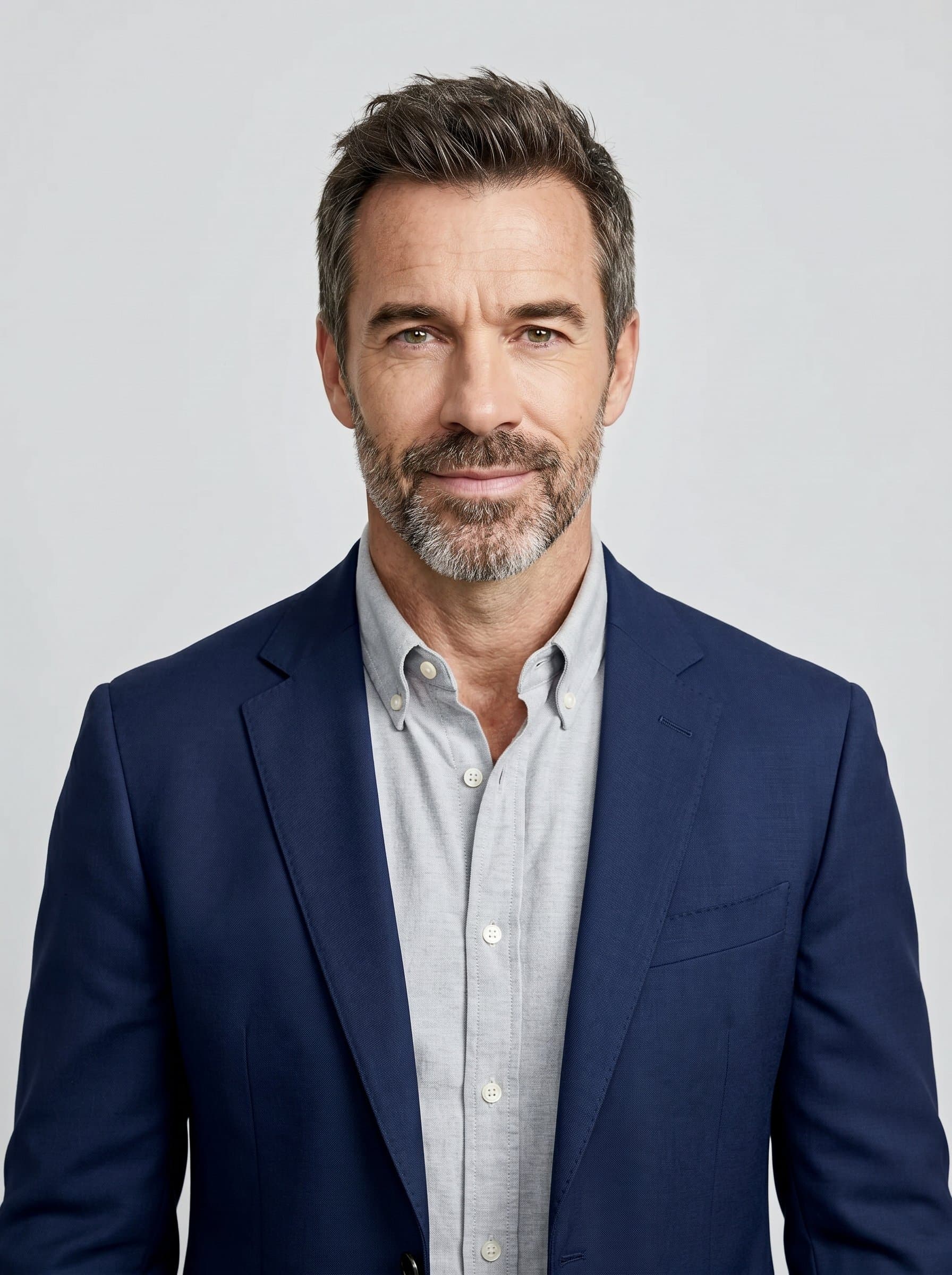 Minimalist headshot with centered and a plain, light grey background, emphasizing a clean and modern approach. The attire should be business casual, ideal for professional networking sites.