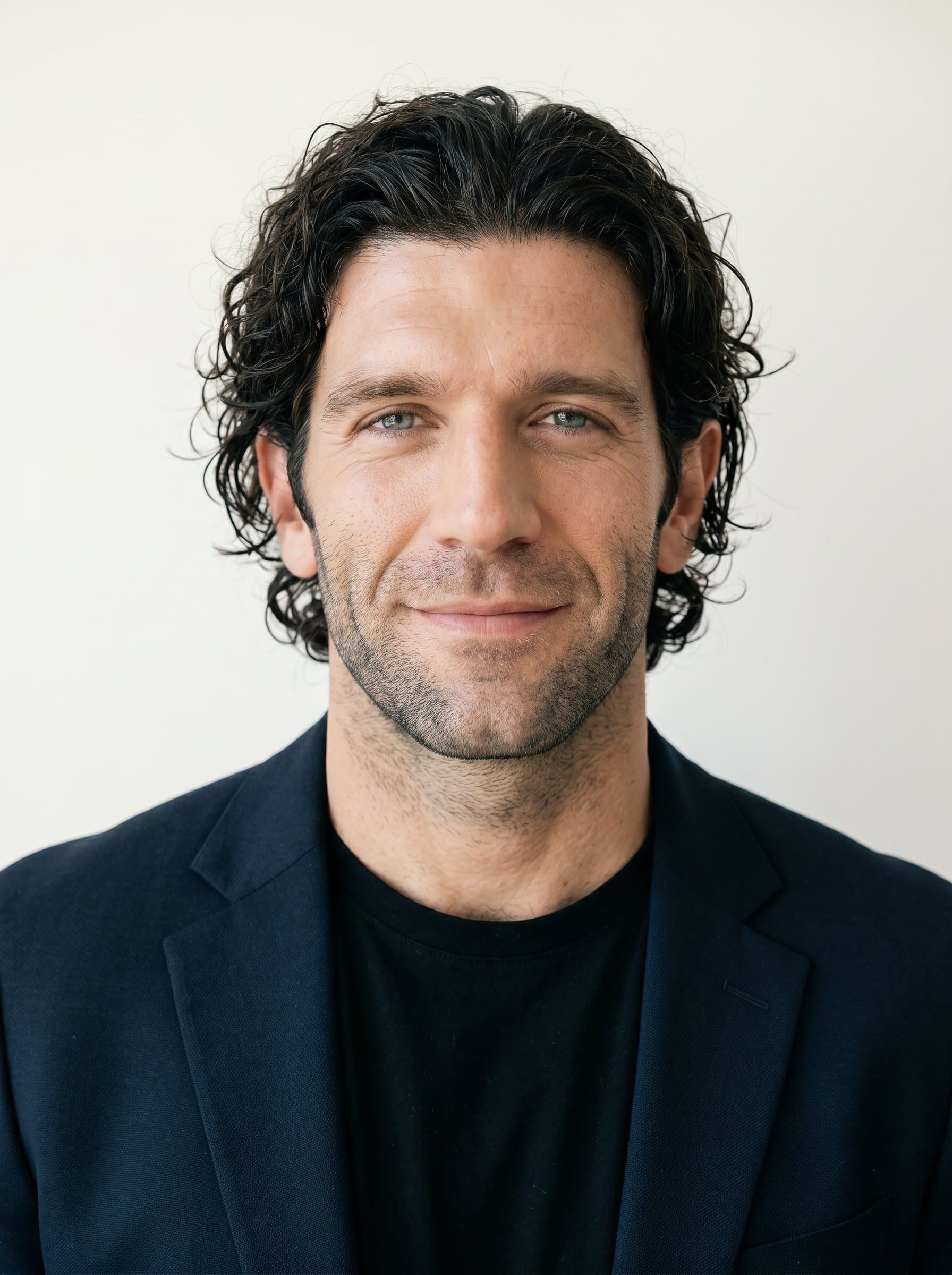 : Deliver a professional yet approachable vibe with a slight smile, using balanced natural lighting to highlight symmetrical features against a soft, matte off-white background.