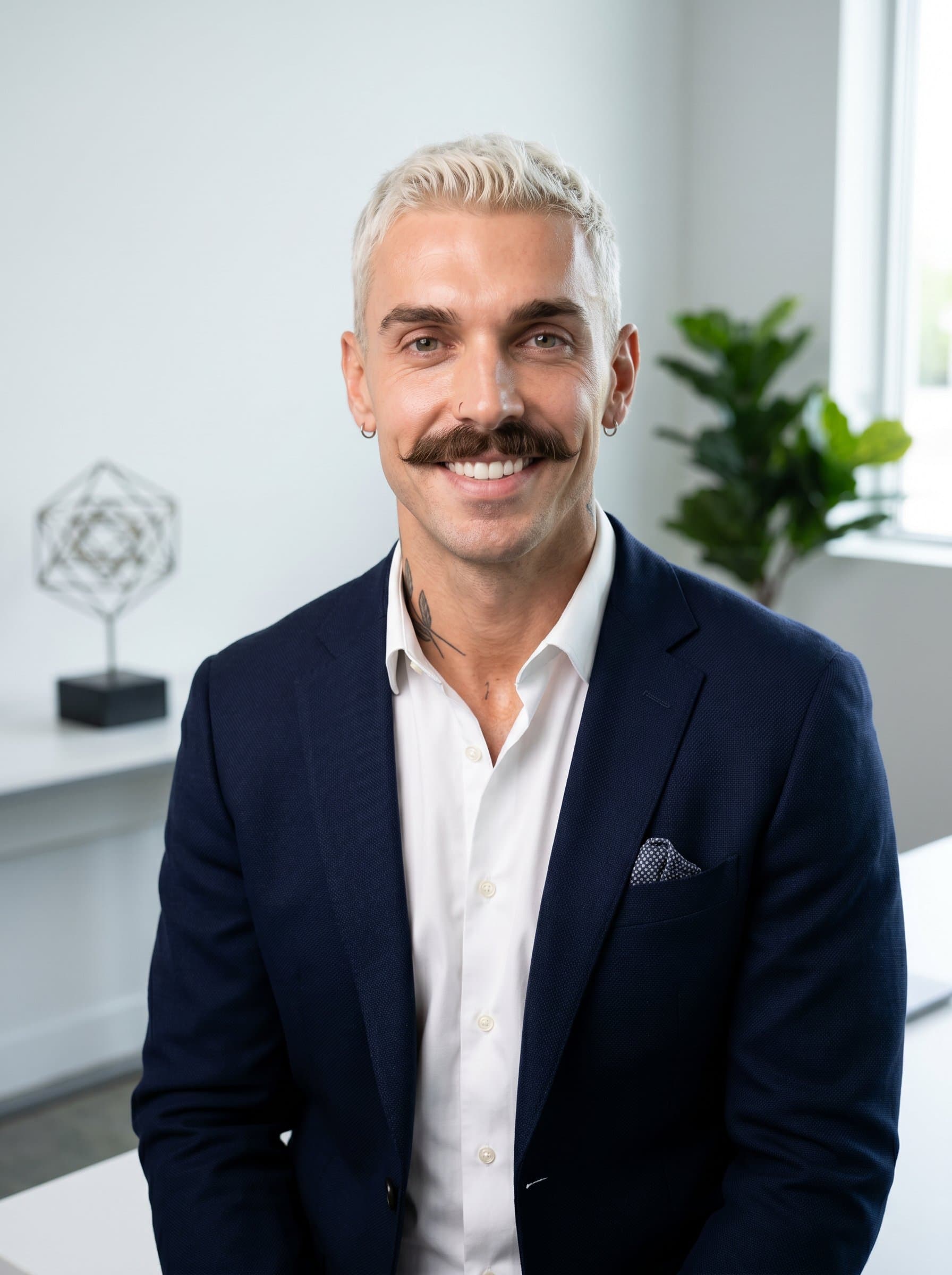 : Create an AI headshot of a CEO in a crisp white shirt and blazer, set in a minimalist office space. The background should display subtle elements of innovation, fostering a sense of forward-thinking and approachability.