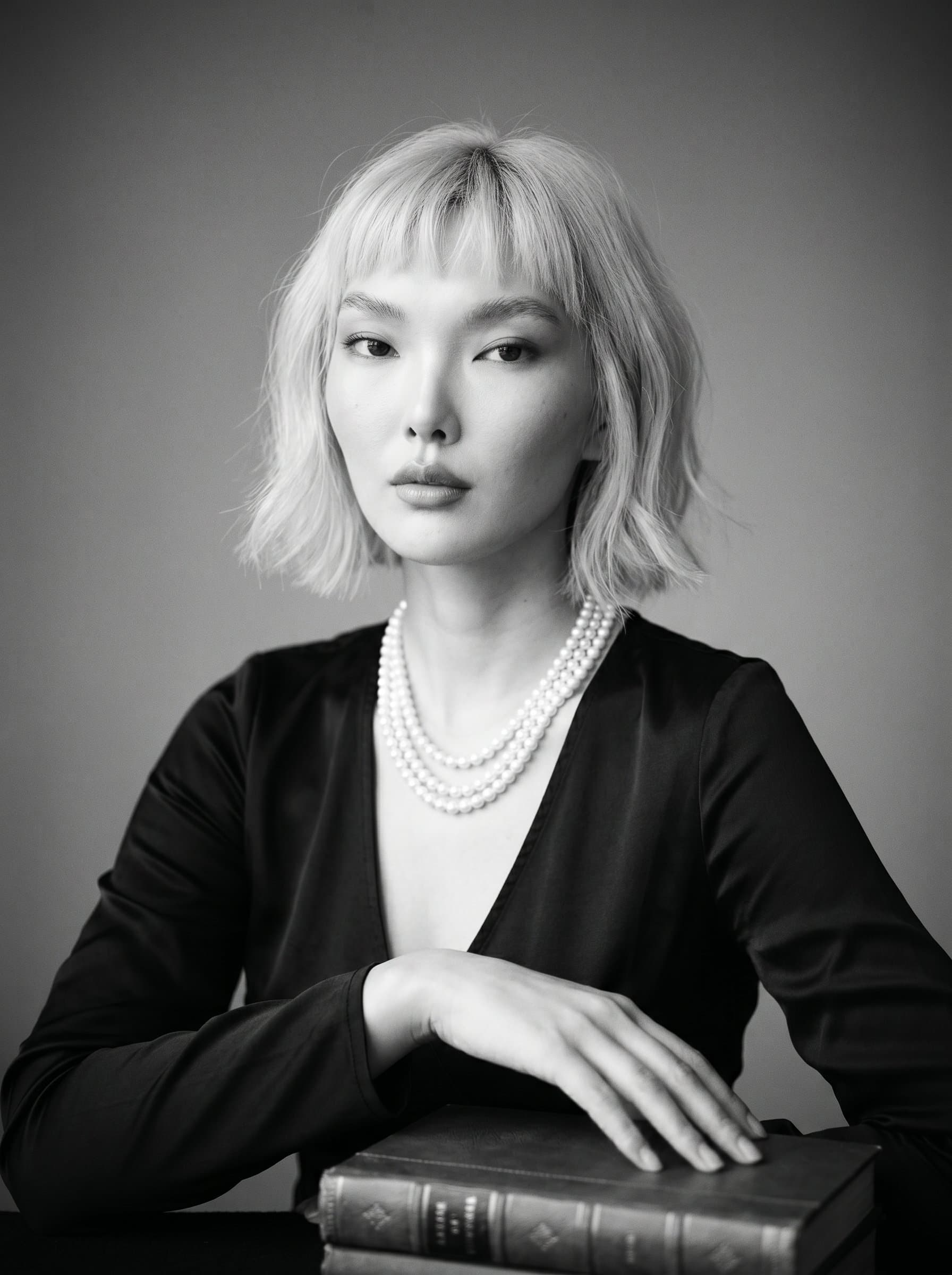 author adorned in Classic Elegance. A black-and-white composition with a soft focus, highlighting the grace and poise of the woman. Neutral gray background enhances the timeless feel.