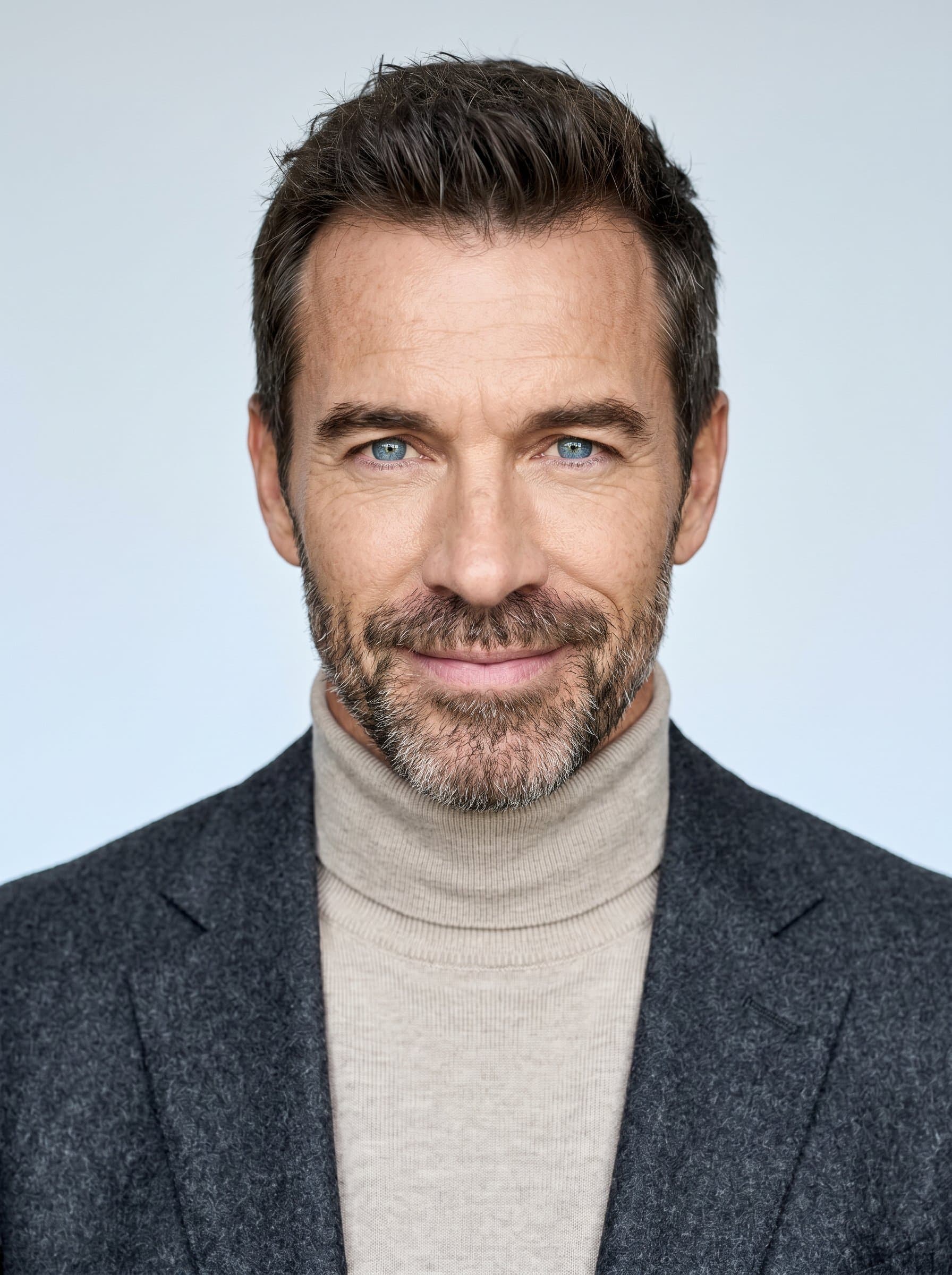 : Minimalist headshot featuring a clean, simple background with subtle color gradients. Focus on the writer's piercing eyes and gentle smile. Sophisticated attire in neutral tones enhances the professional yet approachable feel.