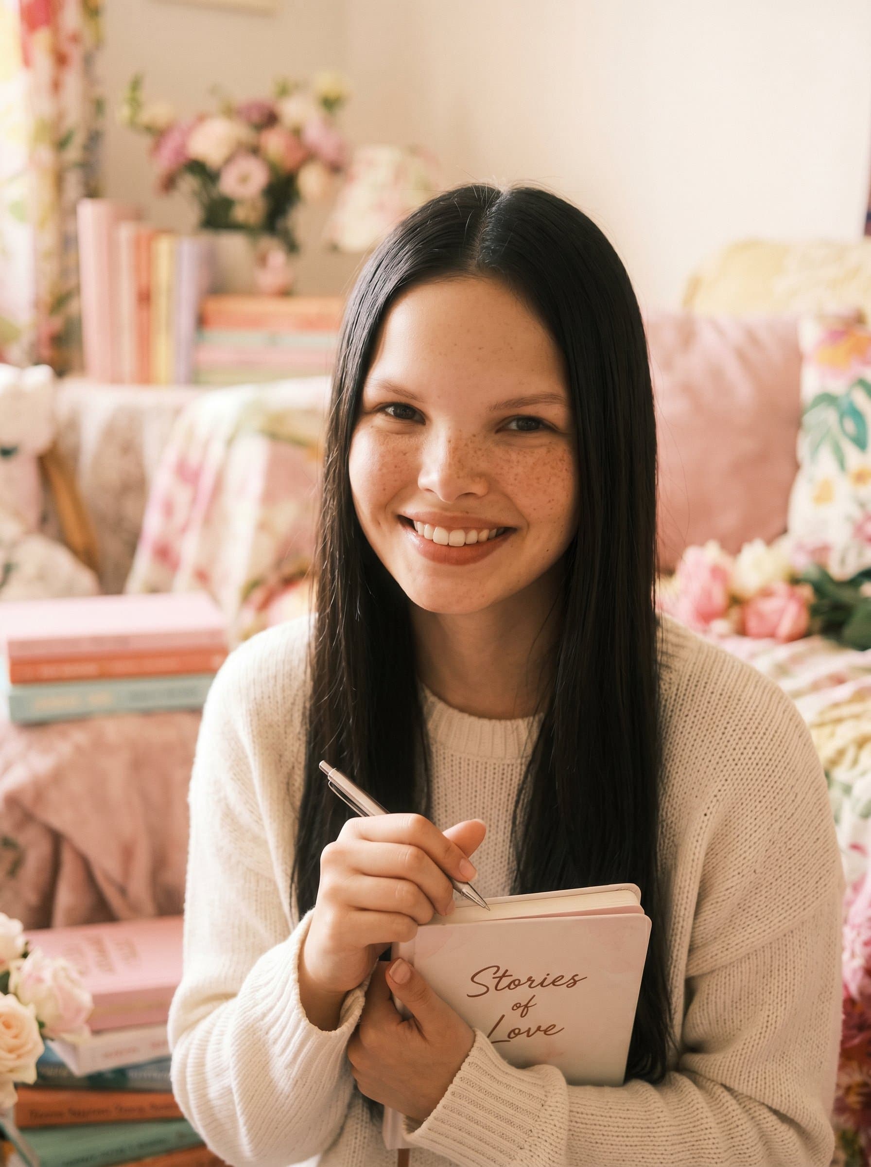 : A romantic fiction writer in a soft-focus headshot with pastel tones. The gentle background complements the warm expression, evoking feelings of love and connection.