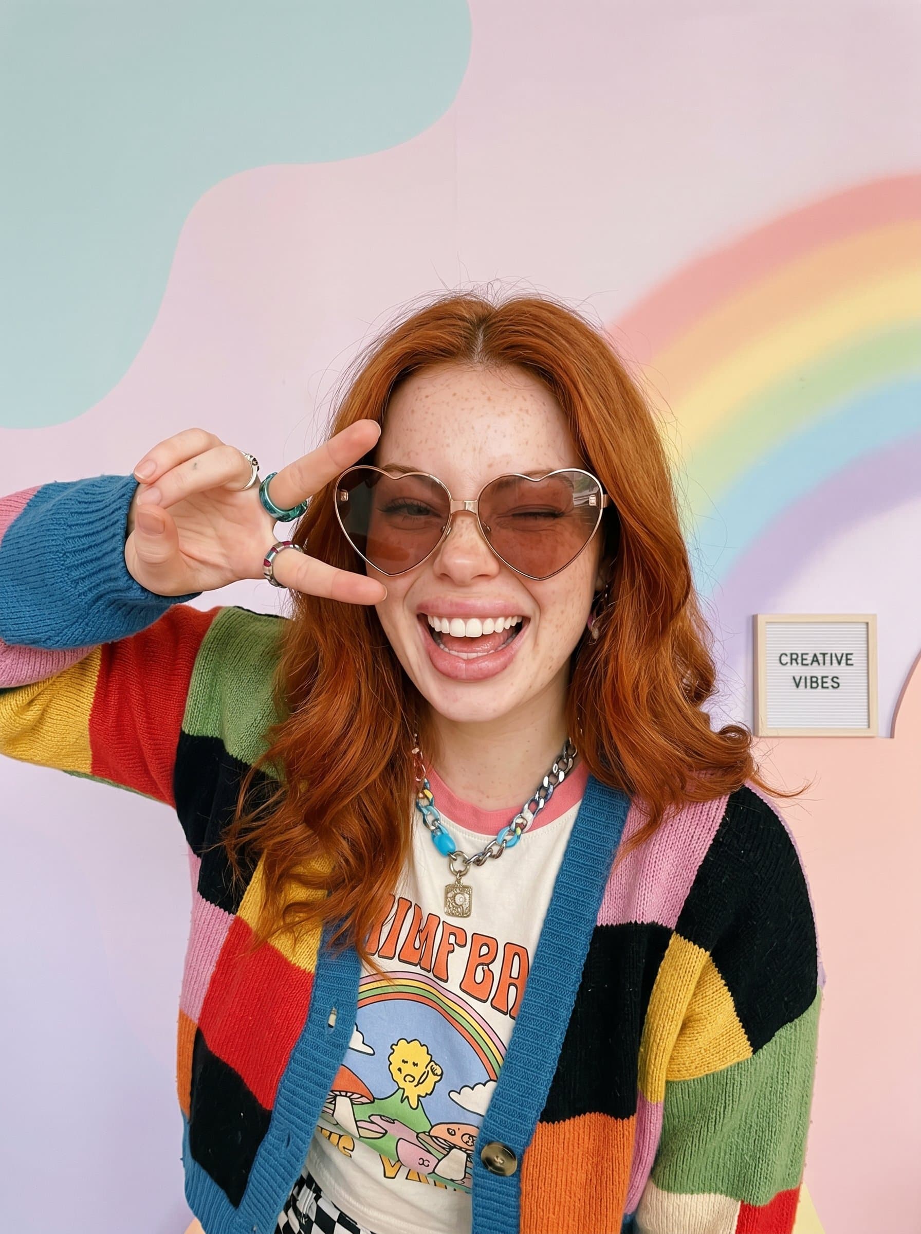 : Playful headshot with pastel-colored backdrop, influencer in quirky outfit, fun and expressive pose, capturing spontaneity, ideal for creative and artistic influencer profiles, vibrant and engaging.