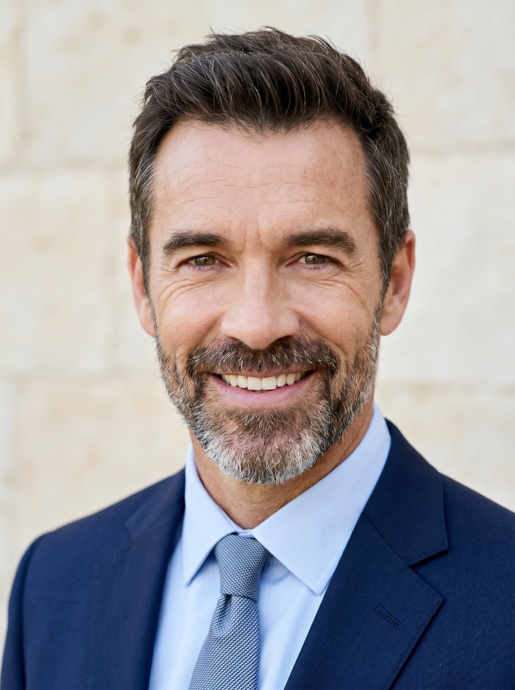 showcases a warm smile, projecting both confidence and friendliness. Set against a light stone background, this headshot is perfect for establishing trust and credibility in the competitive world of journalism.