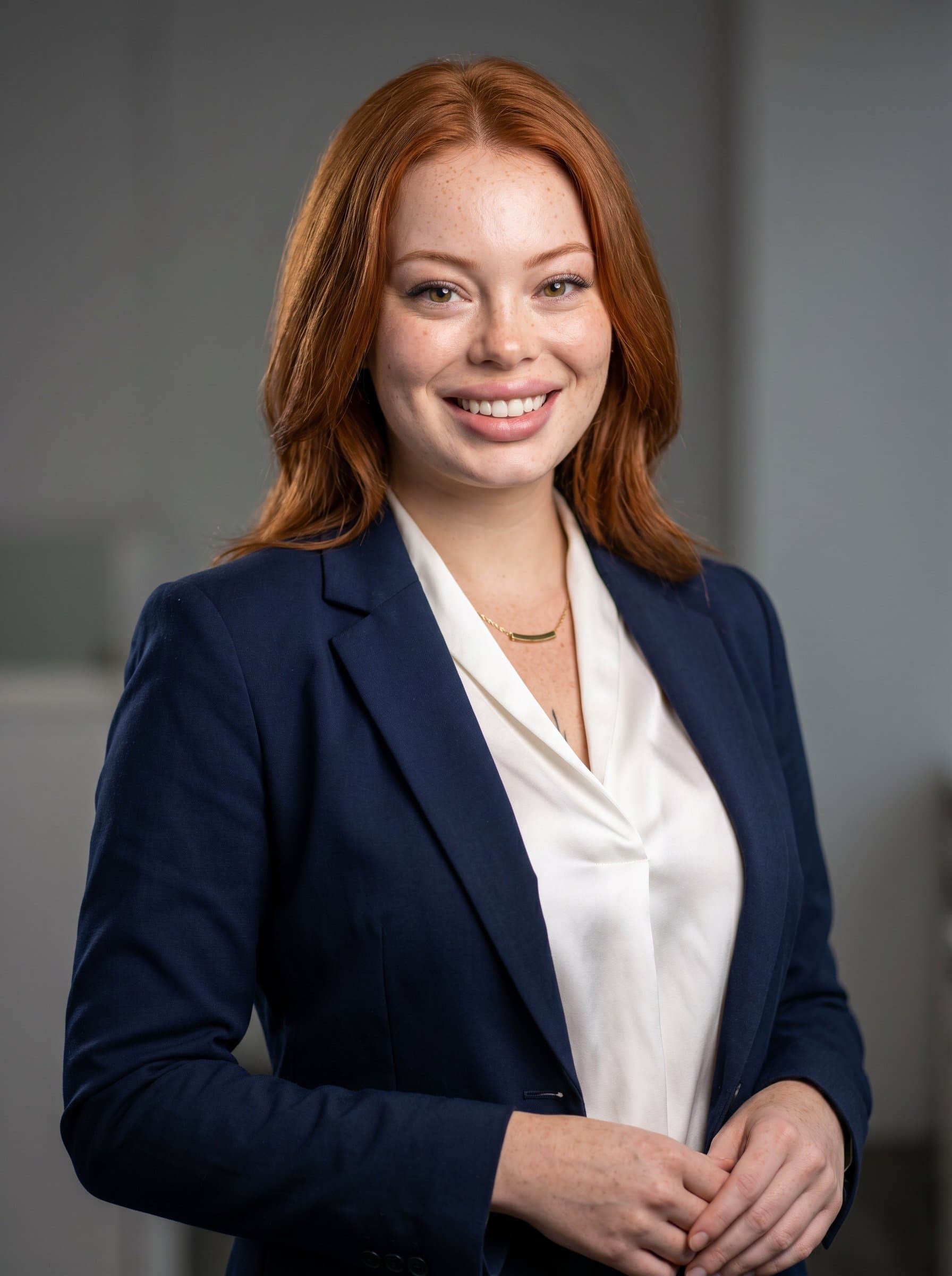 posed confidently in a professional suit against a neutral background. Light highlights key facial features, ensuring a polished, approachable look suitable for a news anchor.