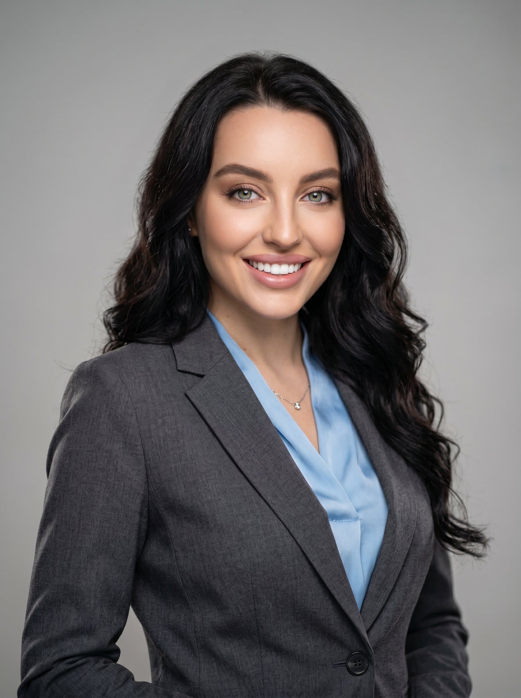 Craft a headshot featuring a speaker with a bright smile, styled in a contemporary business suit. The simple, light background accentuates the speaker's engaging eyes and professional demeanor.