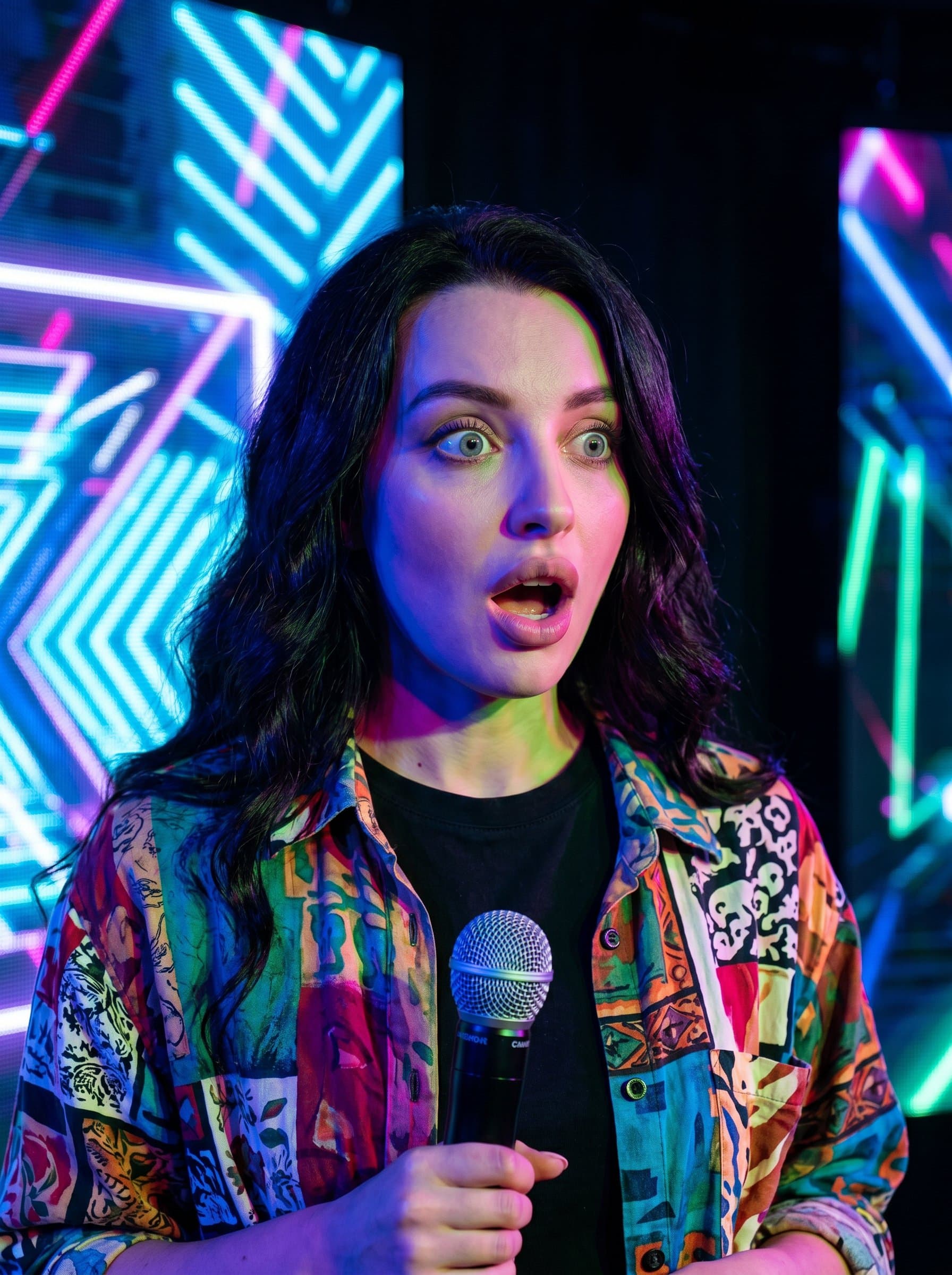 : A headshot capturing a comedian's surprise, features lit with vibrant colored lights. Their eclectic shirt adds personality, standing out in a digital environment with a modern edge.