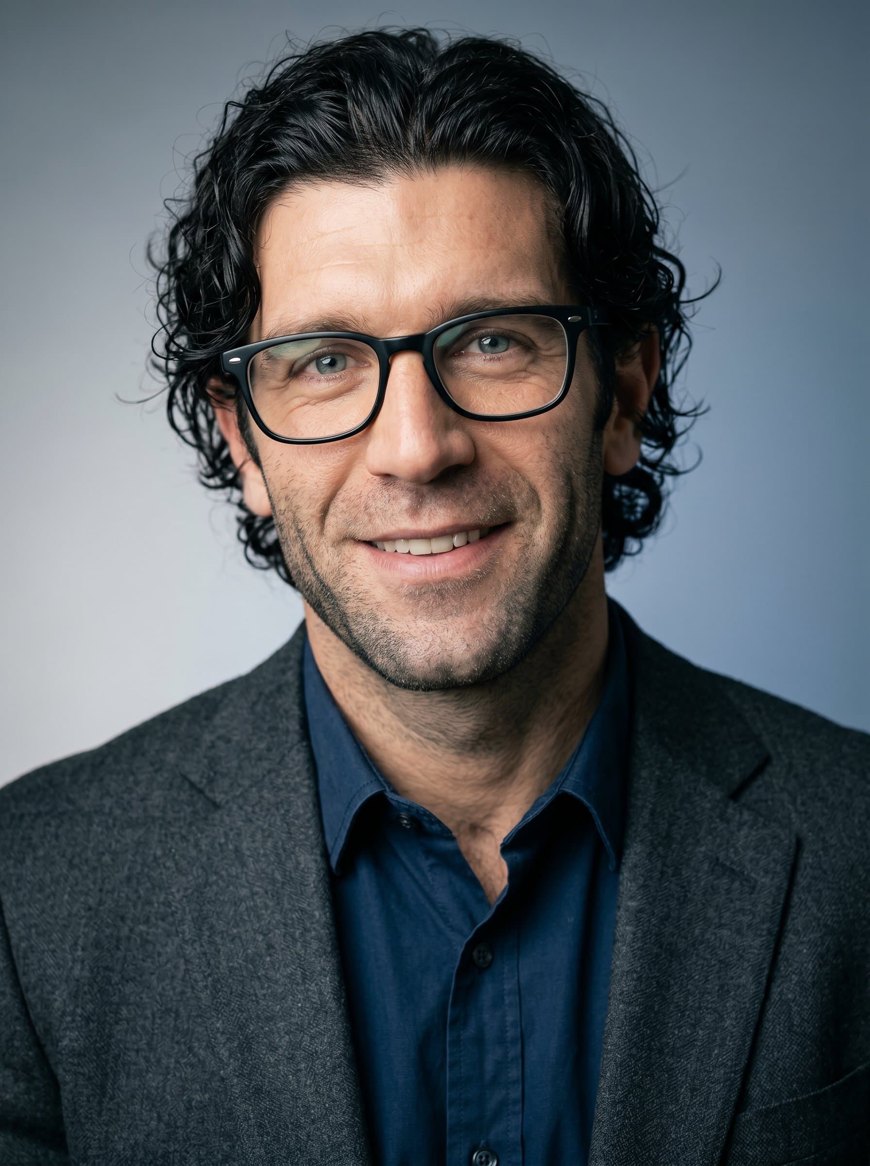 : Portrait of a data scientist with glasses, in a charcoal grey blazer, against a subtle gradient backdrop. The lighting emphasizes the man's focused and approachable personality.