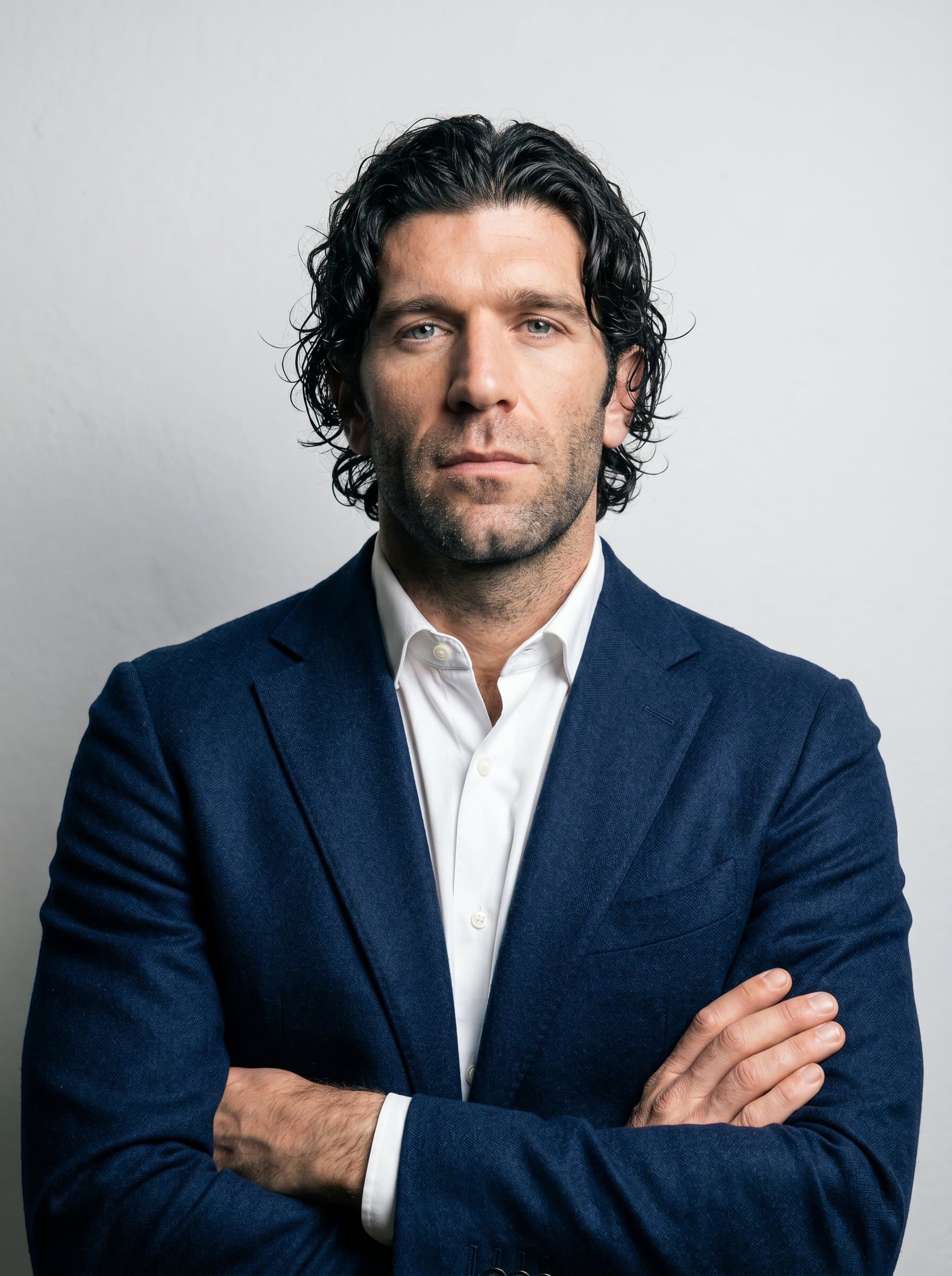 : Portray a solopreneur with a strong-willed expression, in a smart jacket. The clean gray background and focused lighting illustrate their determination and commitment to innovation and personal growth.