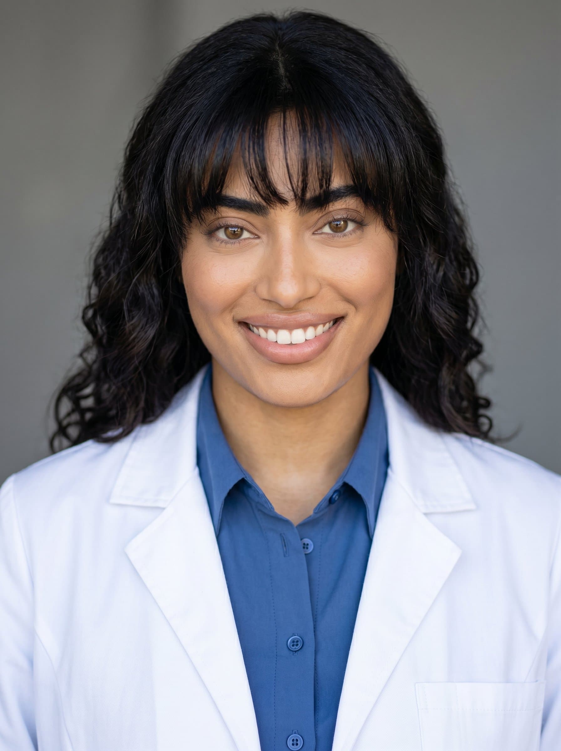 Create a photorealistic AI headshot featuring wearing a white coat. The expression should blend professionalism with warmth, framed by a neutral background to maintain focus on their professional persona.