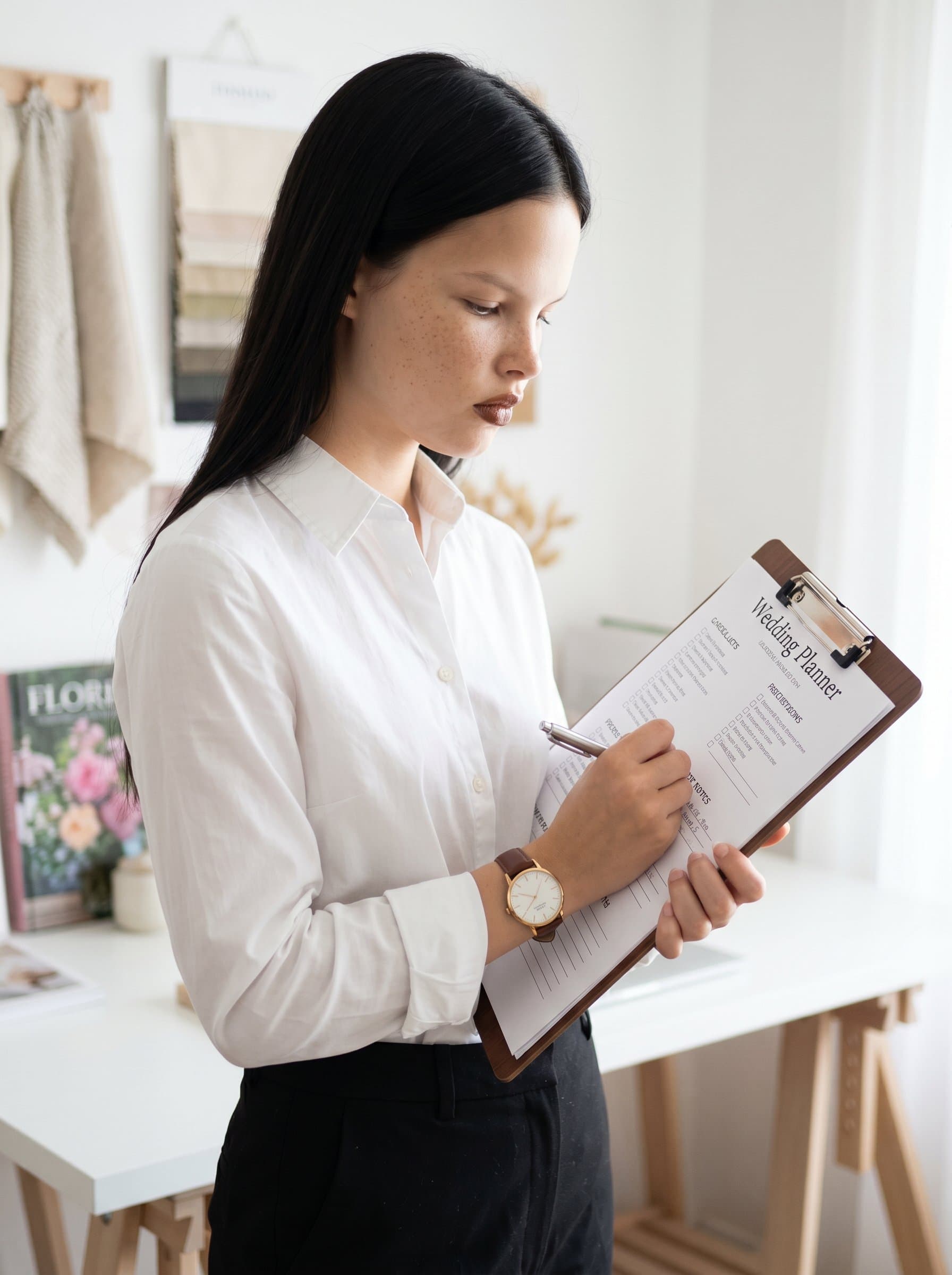 Capture a of a wedding planner with a classic wristwatch, holding a clipboard. Use soft, diffused lighting and a simple, clean background to emphasize their organized and meticulous nature.