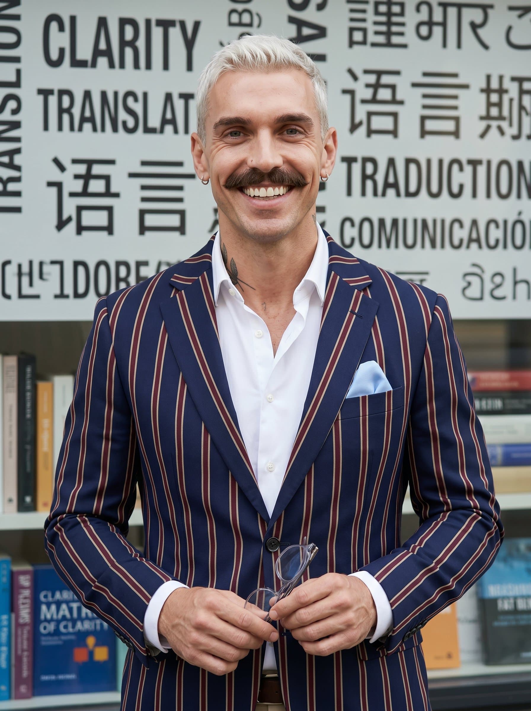 Against a backdrop of gently blurred multilingual text, a translator in a tailored outfit beams confidently, demonstrating clarity and expertise.