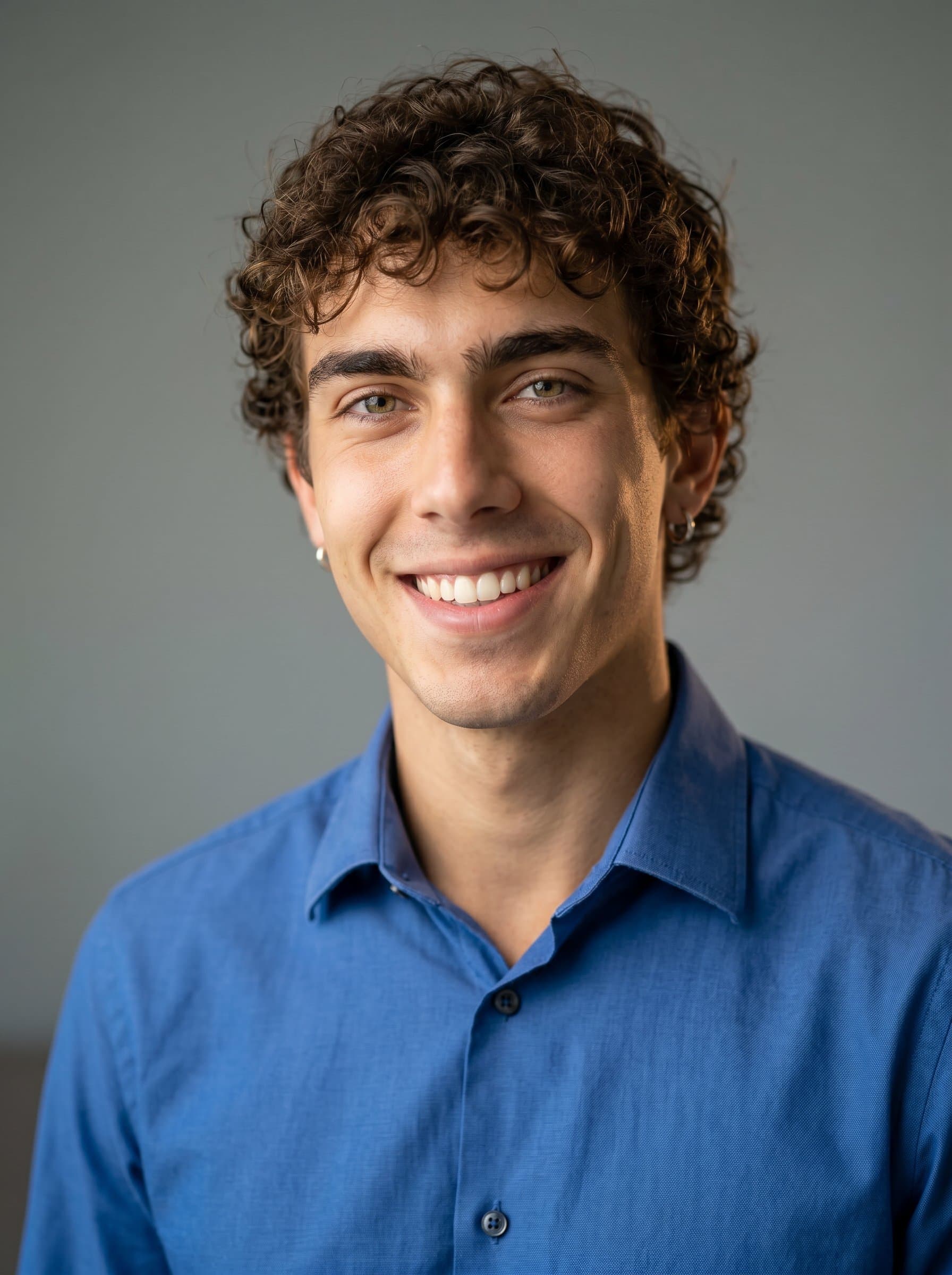 is captured mid-smile, wearing a professional, buttoned-up shirt. The quiet elegance of the soft gray background adds a sense of trustworthiness and approachability essential for school administrators.