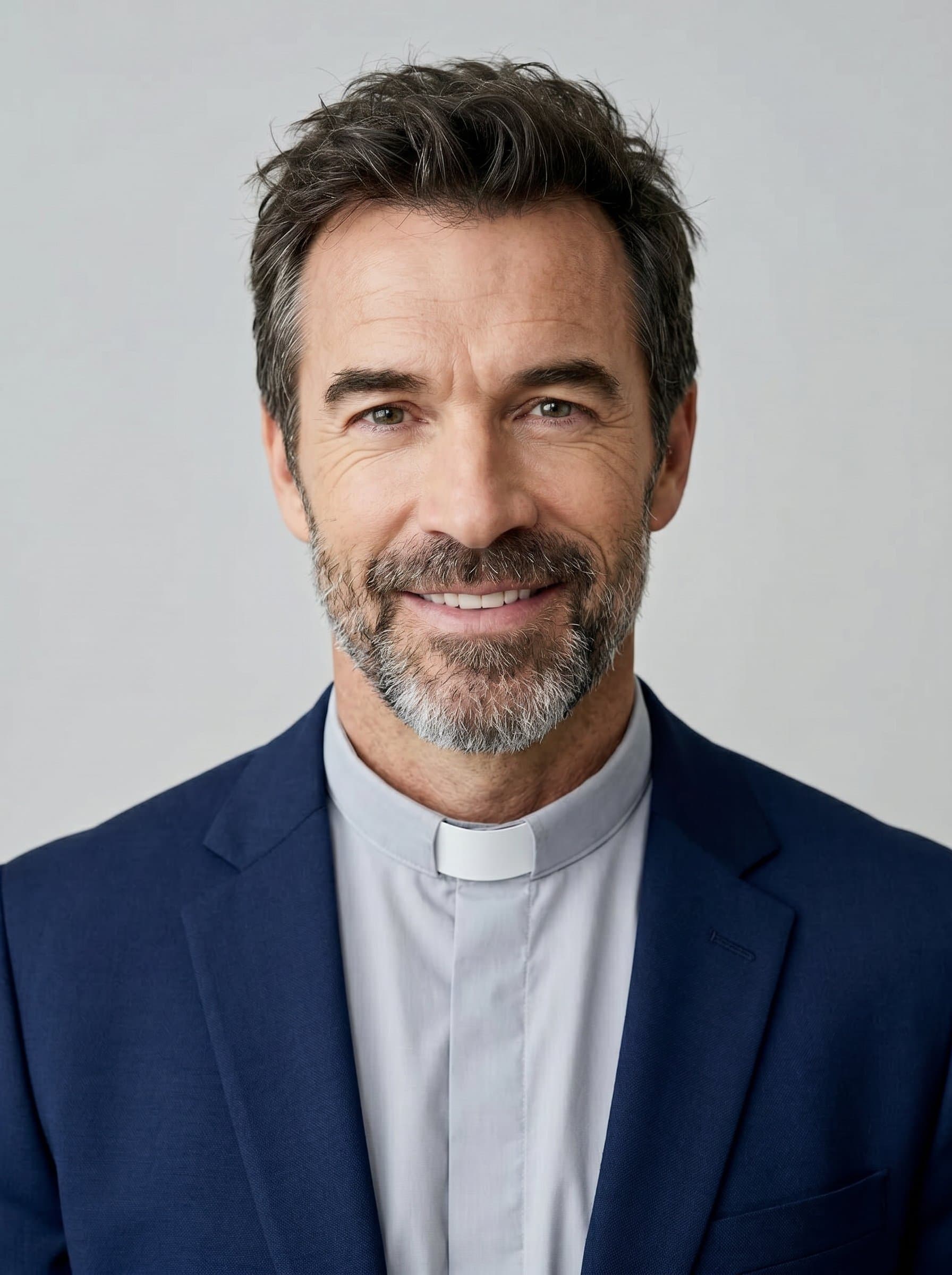 : Create a headshot of a pastor with a serene expression, gently tousled hair, clad in a modest yet classy navy blue blazer, with a light gray background that highlights their approachable nature.