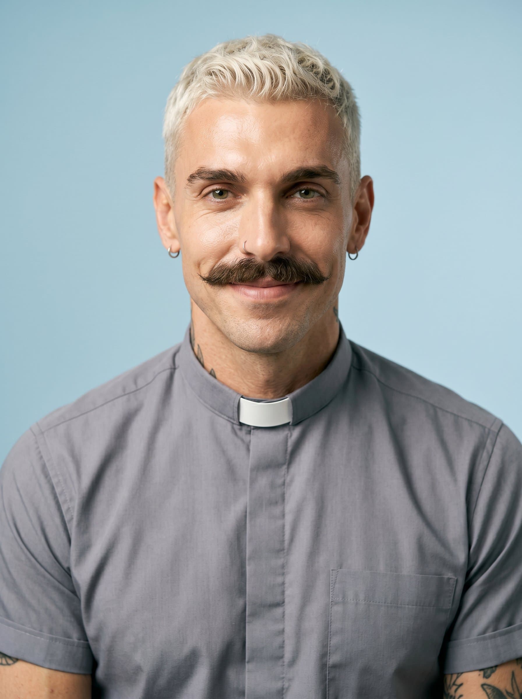 : Professional headshot of a pastor with a gentle and understanding demeanor, in a neat gray clerical shirt, set against a soft pastel blue backdrop, conveying peace and spiritual guidance.