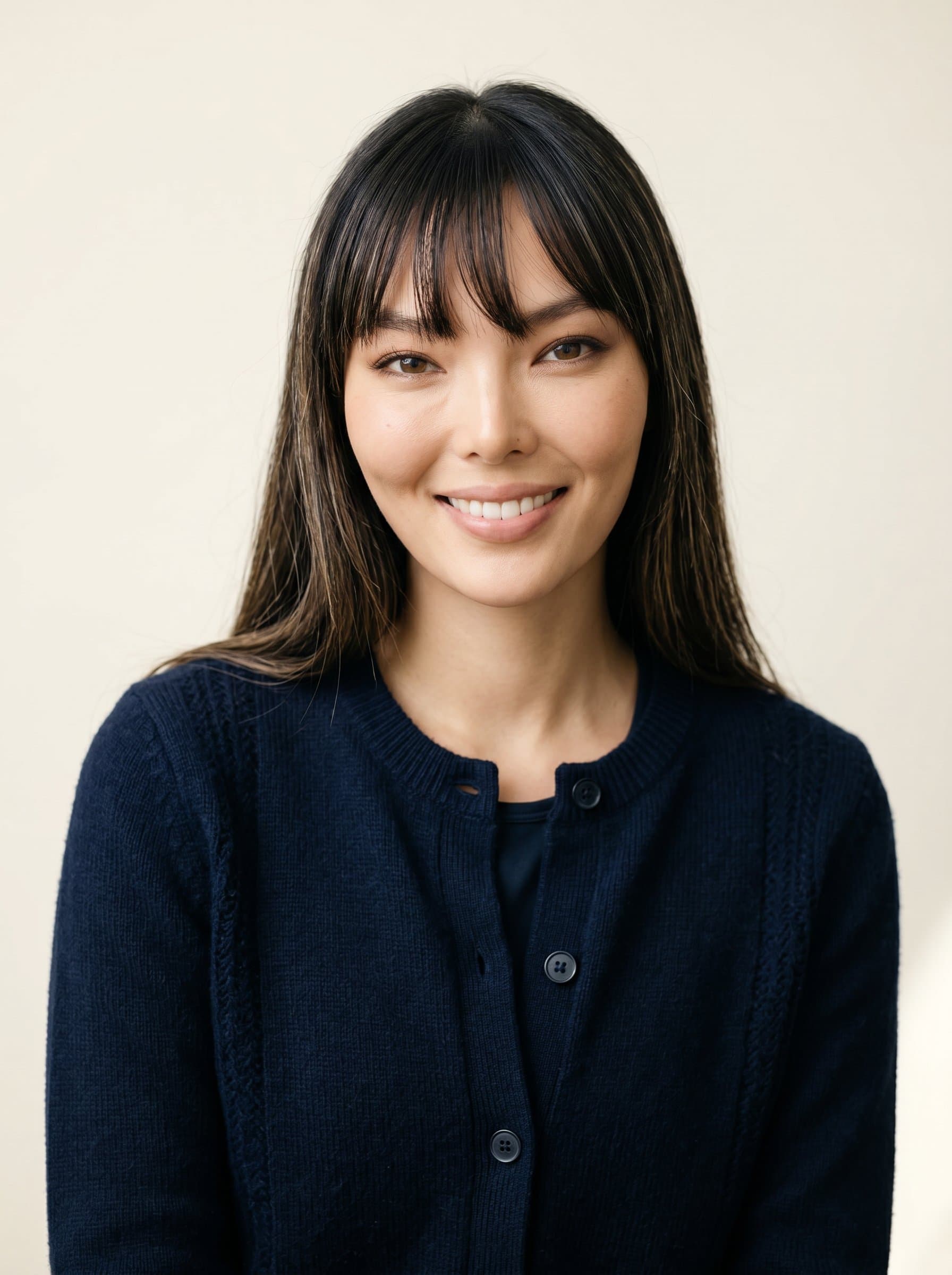 : A detailed headshot of a pastor with a compassionate smile, clad in a simple yet stylish navy cardigan, set against a soft cream-colored background, highlighting their role as a trusted advisor.