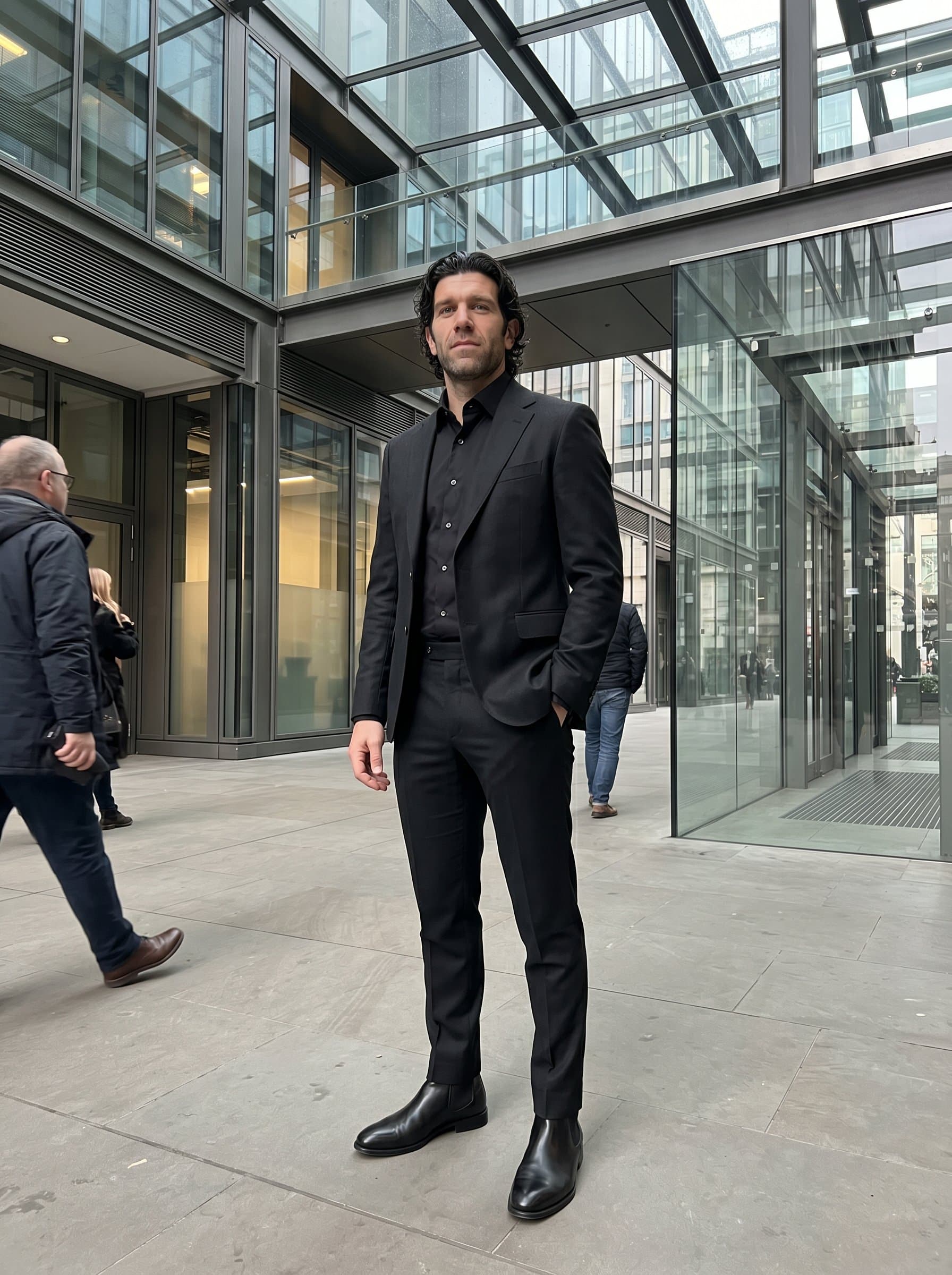 standing amidst sleek steel and glass architecture, in a sharp black ensemble, exuding a sense of precision and contemporary style.