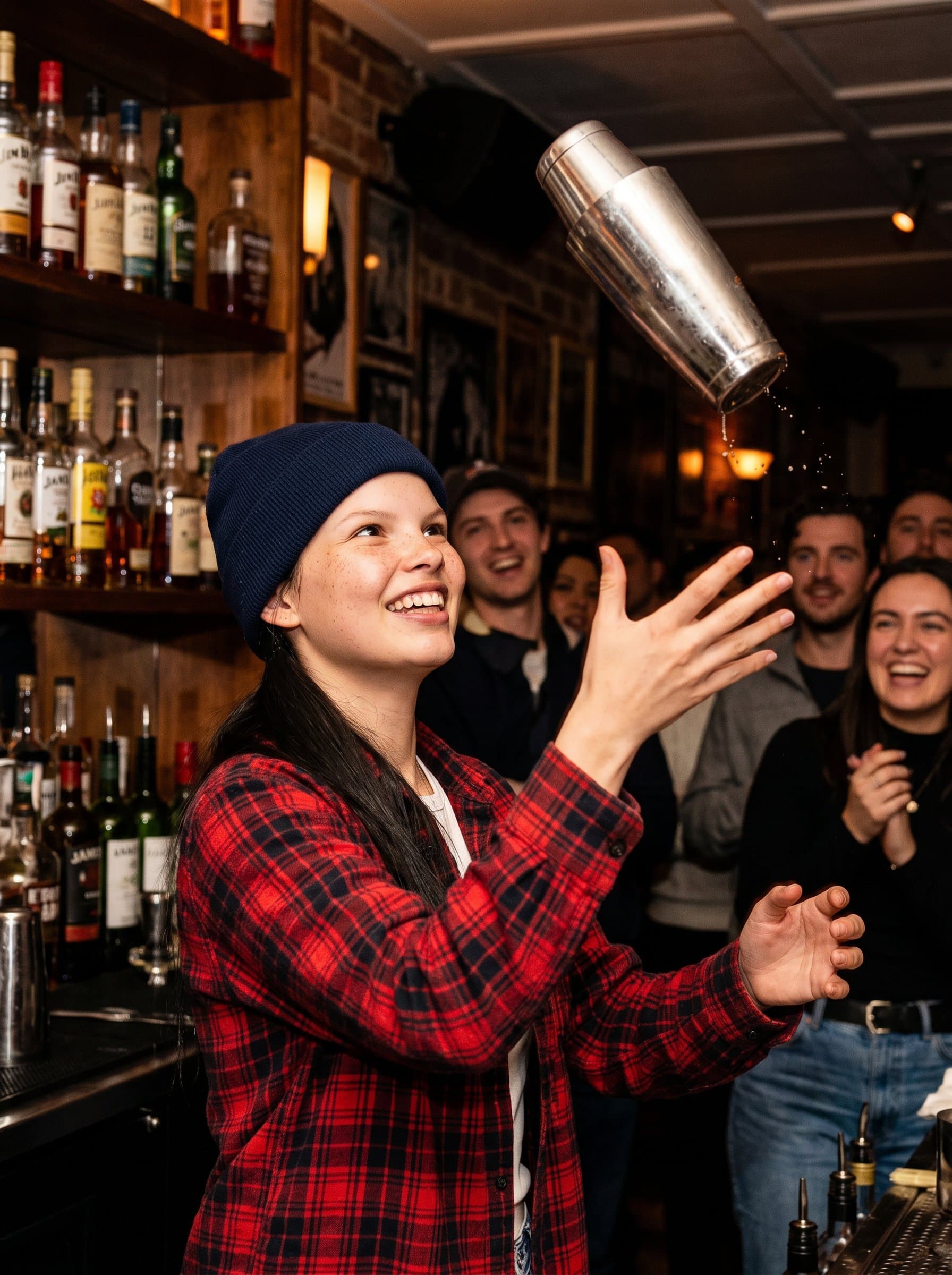 : A dynamic bartender with a casual vibe, sporting a beanie and flannel shirt, throwing a cocktail shaker in the air amidst a bustling bar scene with patrons eagerly watching.
