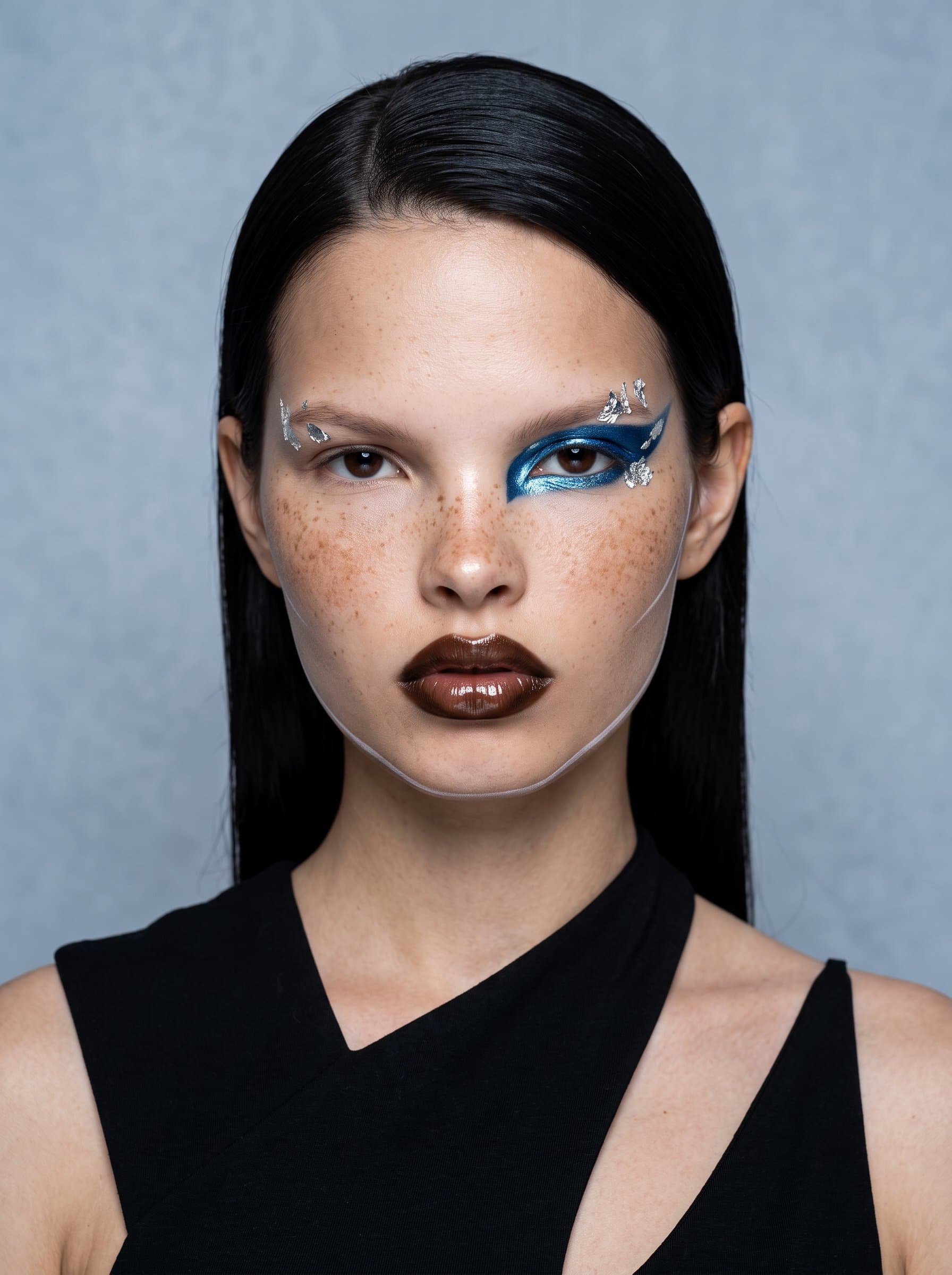 Capture a with an editorial, high-fashion makeup style. The pale slate backdrop accentuates the dramatic and unconventional elements of their innovative artistry.