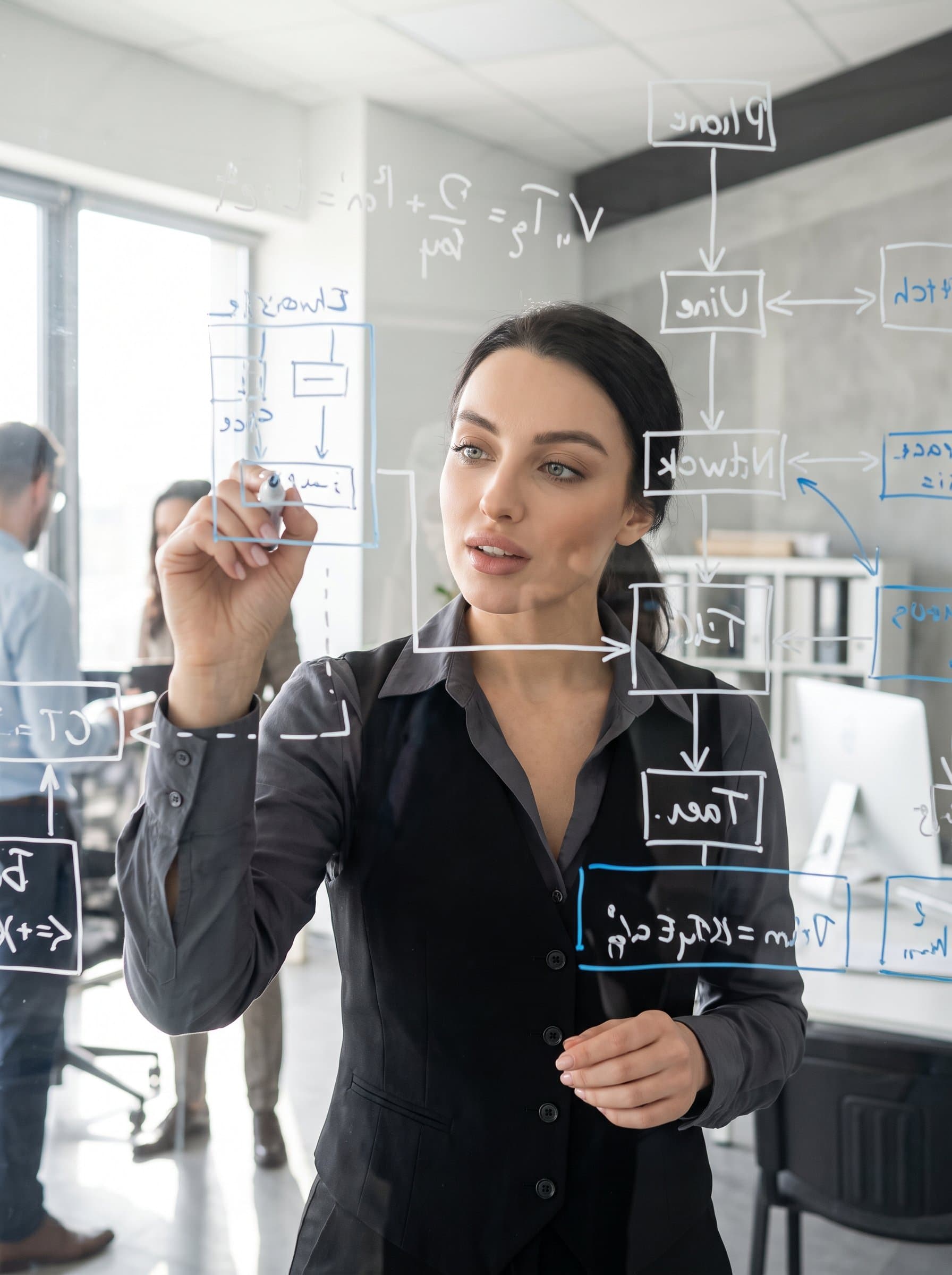 captured in a moment of inspiration, jotting notes on a glass marker board with tech diagrams. Their attire is modern and relaxed, with an open collar shirt under a sleek vest.