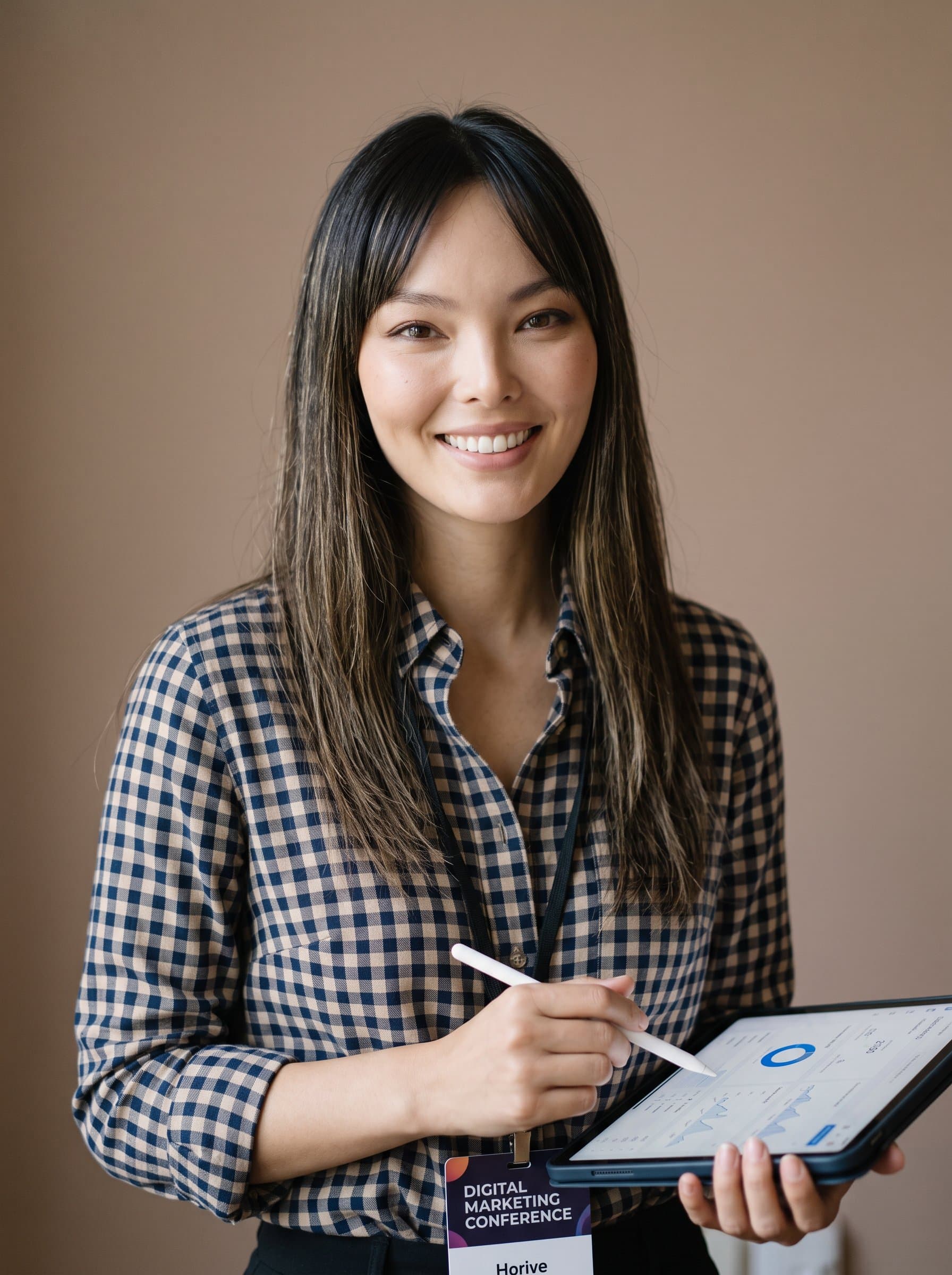 places focus on a smiling media strategist, wearing a checked shirt. Their approachable nature shines through a minimalist light brown background.