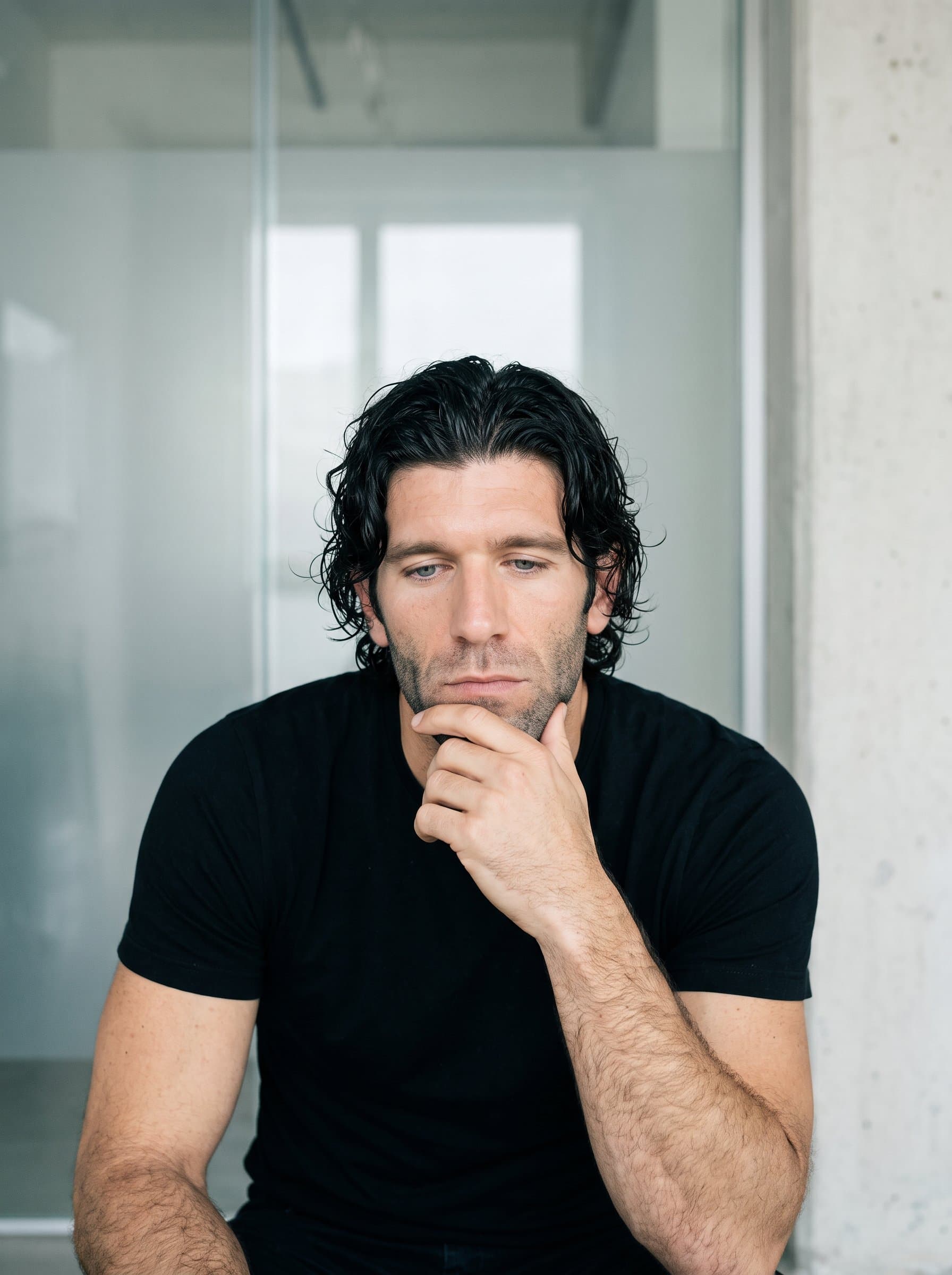 captured in a candid moment of reflection, framed by a simple, light-colored background that hints at transparency and integrity.