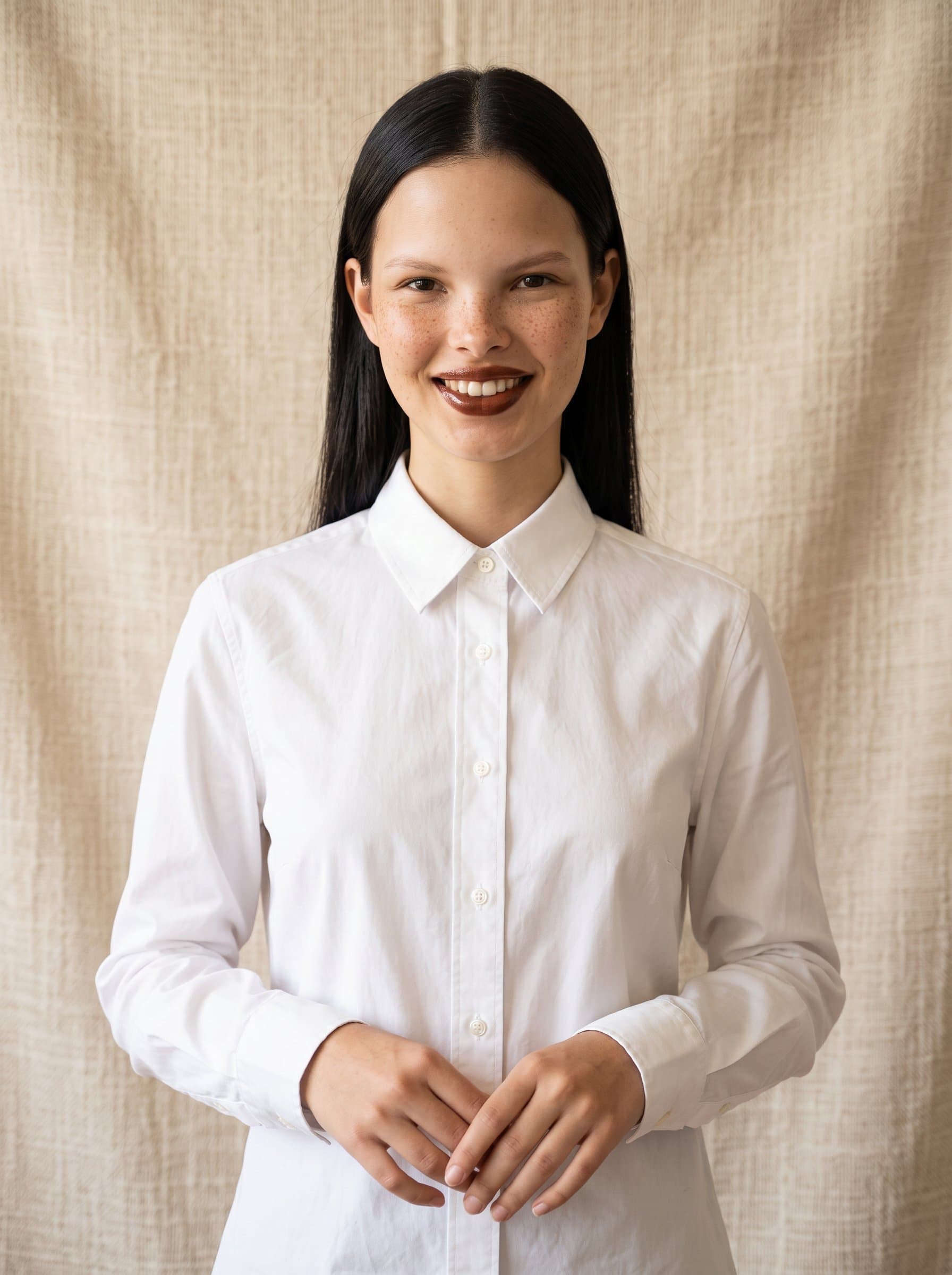 with a relaxed, confident posture, in front of a textured, neutral shade backdrop that hints at approachability and accessibility.