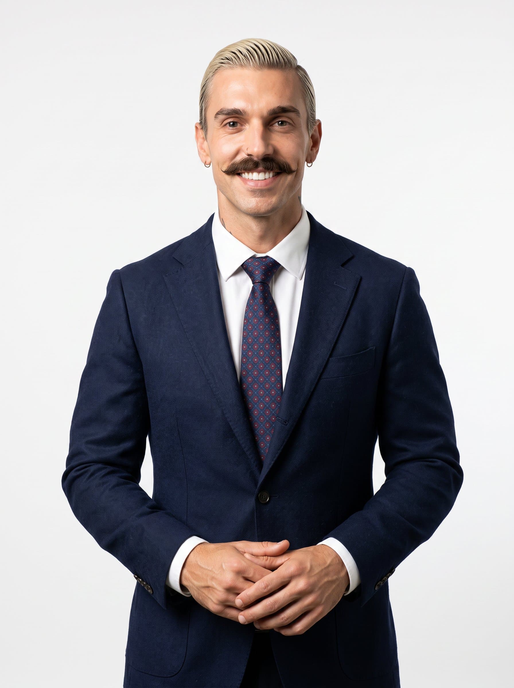 : Portrait of a startup advisor with slicked-back hair and a sharp blazer, standing against a plain white backdrop. The emphasis is on professionalism and clarity.