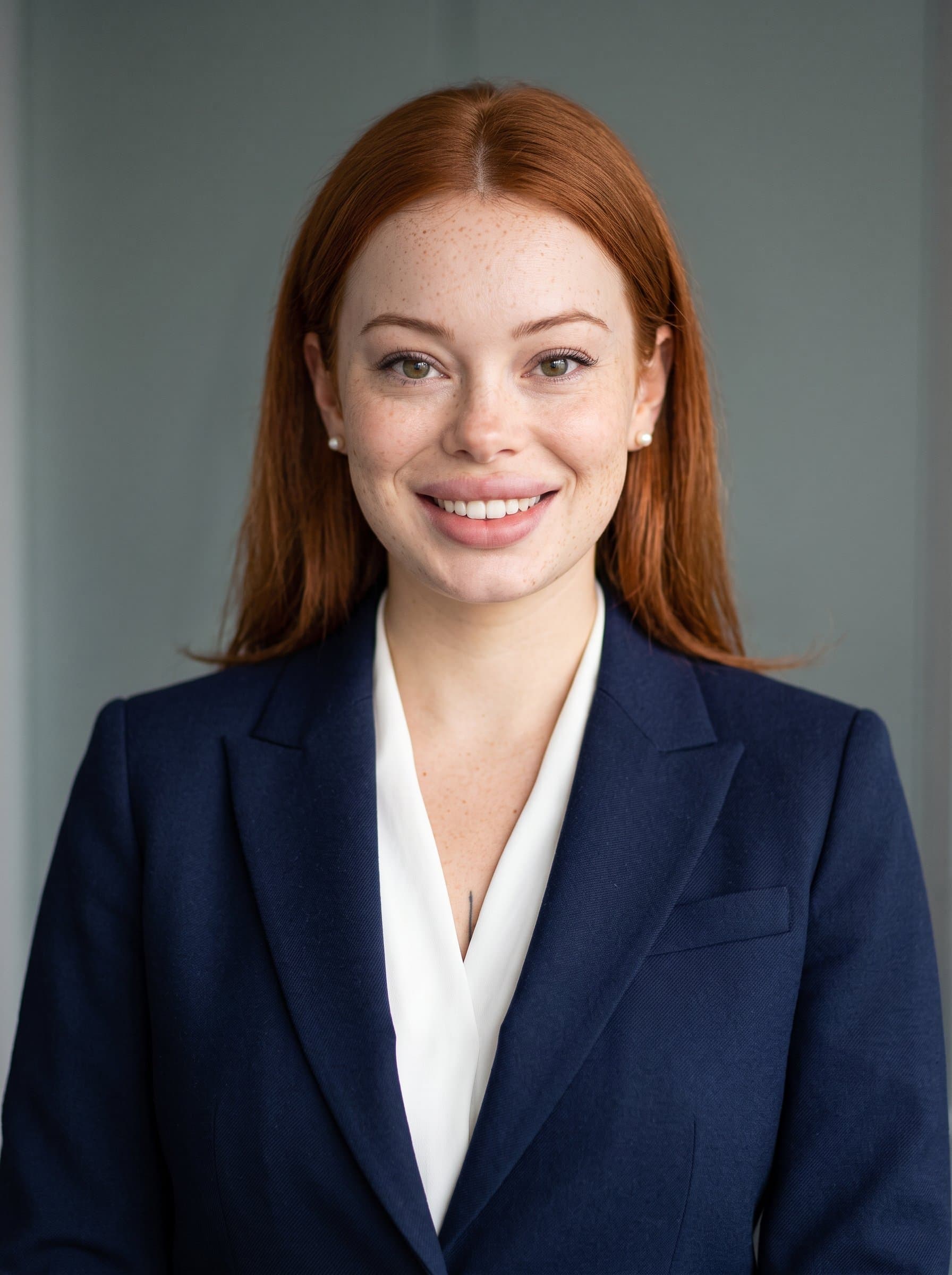 A professional headshot of against a muted background, dressed in an impeccably fitting blazer, exuding confidence and warmth, representing a trusted figure in the pharmaceutical industry.