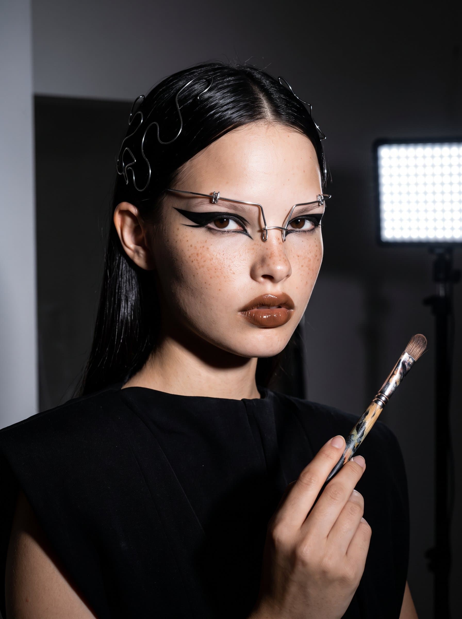 : Produce an editorial AI headshot emphasizing high contrast and avant-garde styling, with distinctive makeup and accessories, for a visionary artist in the beauty editorial world.