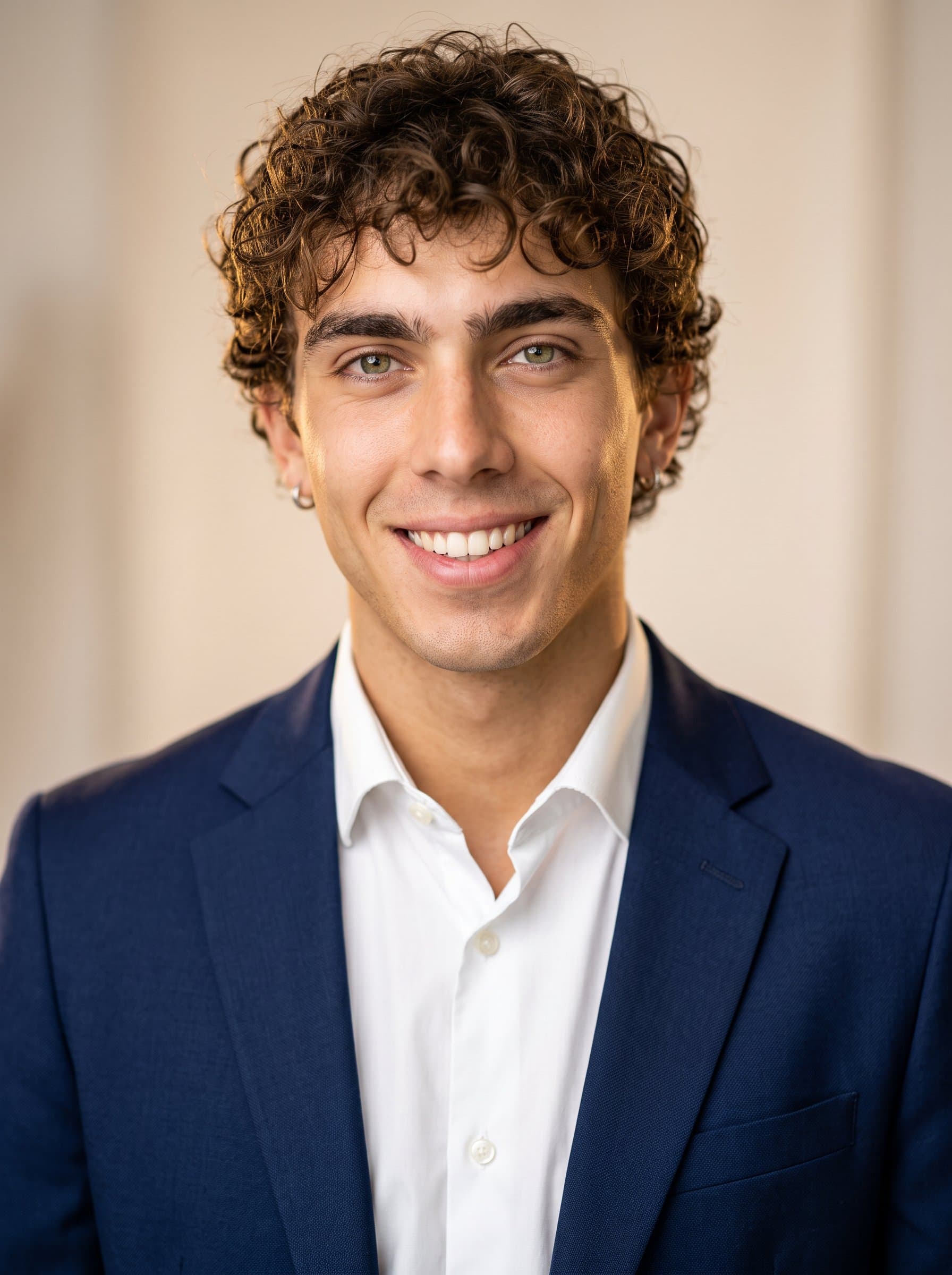 : Create a headshot with a faculty member wearing a navy blazer and white shirt. The background is a light beige, with warm lighting accentuating a poised and approachable demeanor.