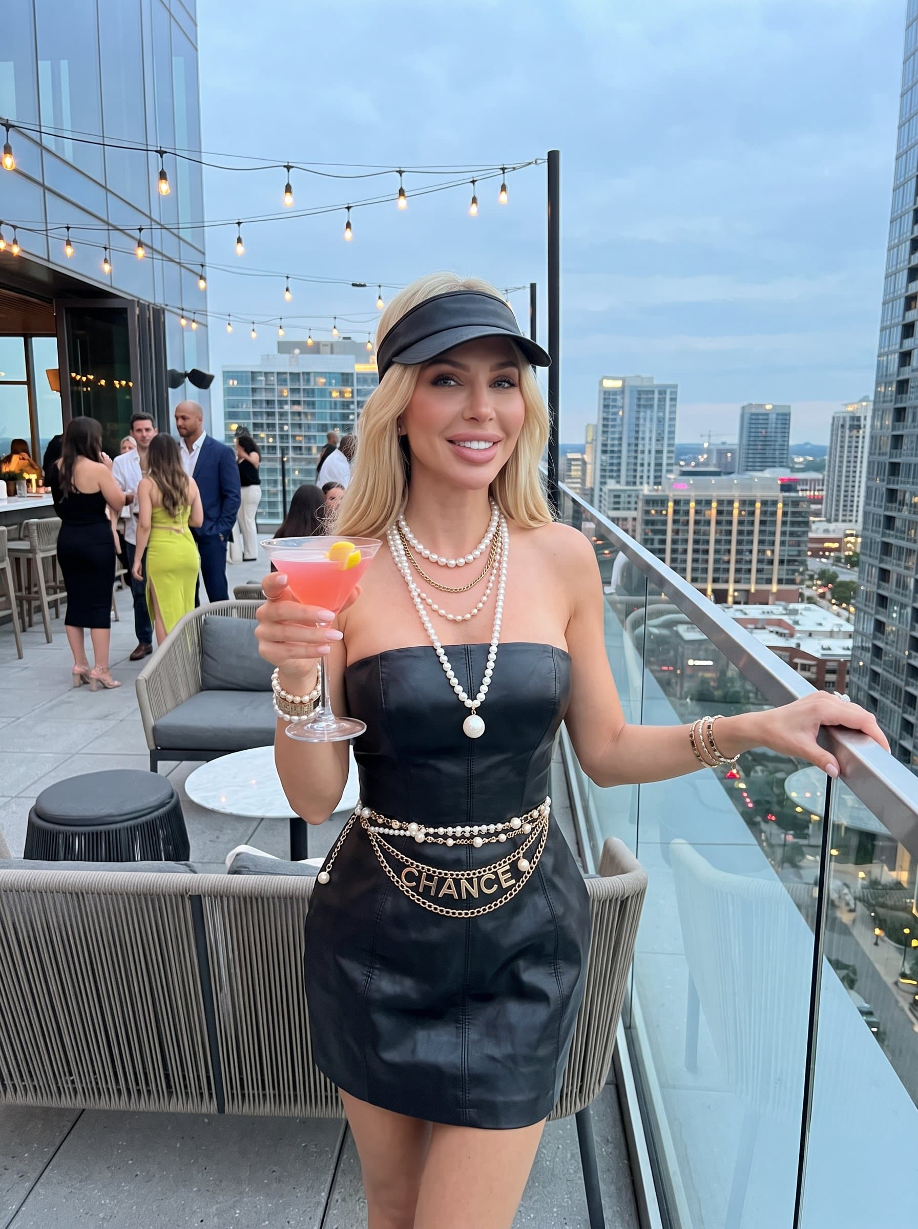 Present the at a chic rooftop bar, holding a cocktail. The trendy setting and confident pose convey a social butterfly with a taste for the finer things.