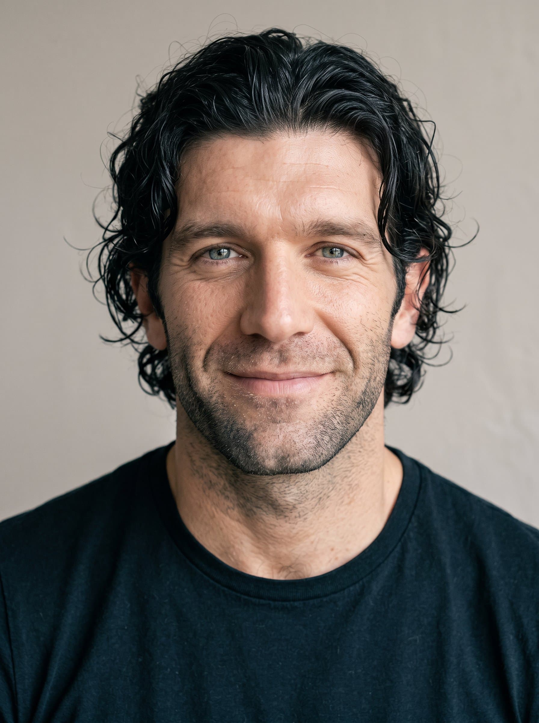 : Capture a minimalist headshot with a neutral color palette and subtle lighting. The man's relaxed smile should convey authenticity, perfect for a straightforward and genuine brand image.