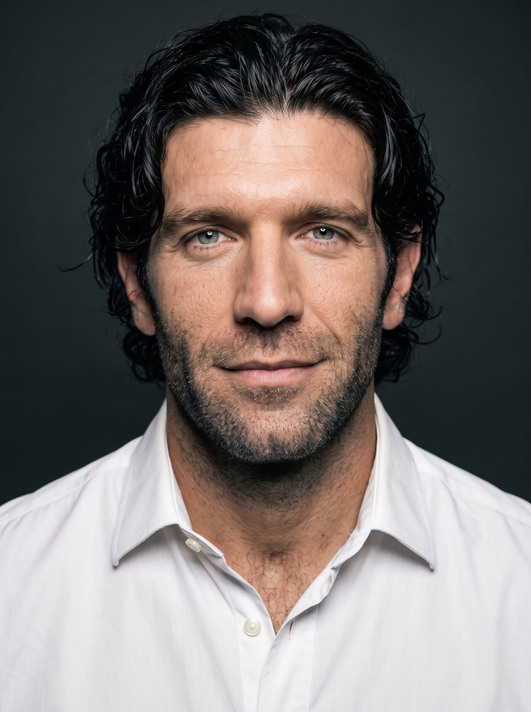 : Generate a striking headshot, focusing on contrast and sharpness. The man is positioned against a dark, neutral backdrop, wearing a crisp, white button-up, perfect for a polished resume look.