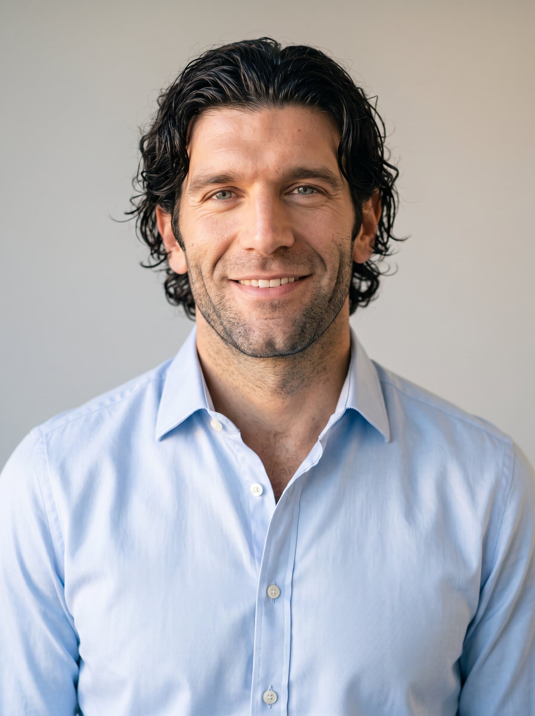 Generate a headshot of a man wearing a crisp shirt, set against a neutral backdrop. The lighting should be soft, adding warmth and approachability to the professional appearance.