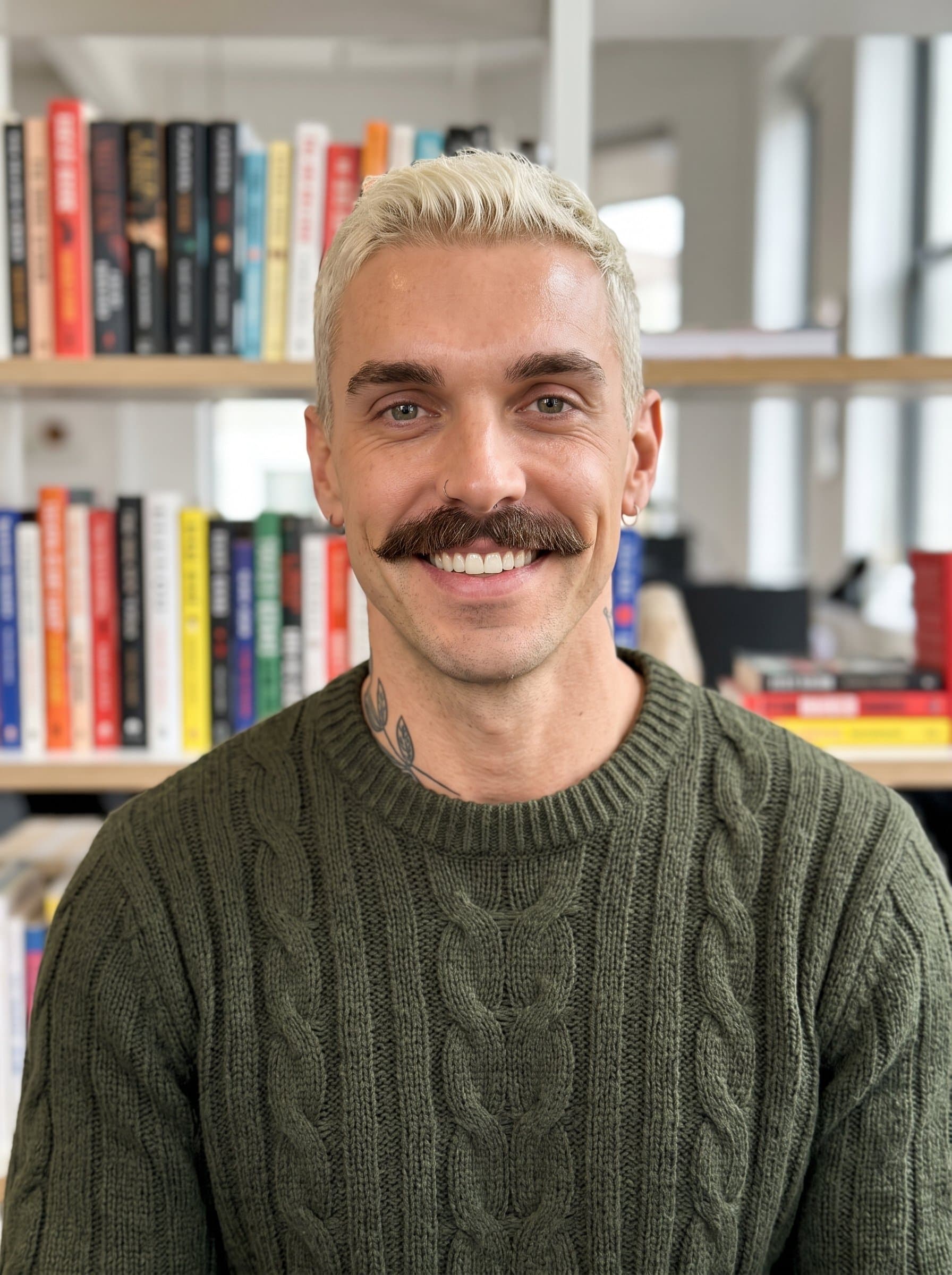 A minimalist headshot of in an open office environment, with shelves of books in the background, dressed in a cozy sweater, conveying warmth and intelligence for a publishing company.