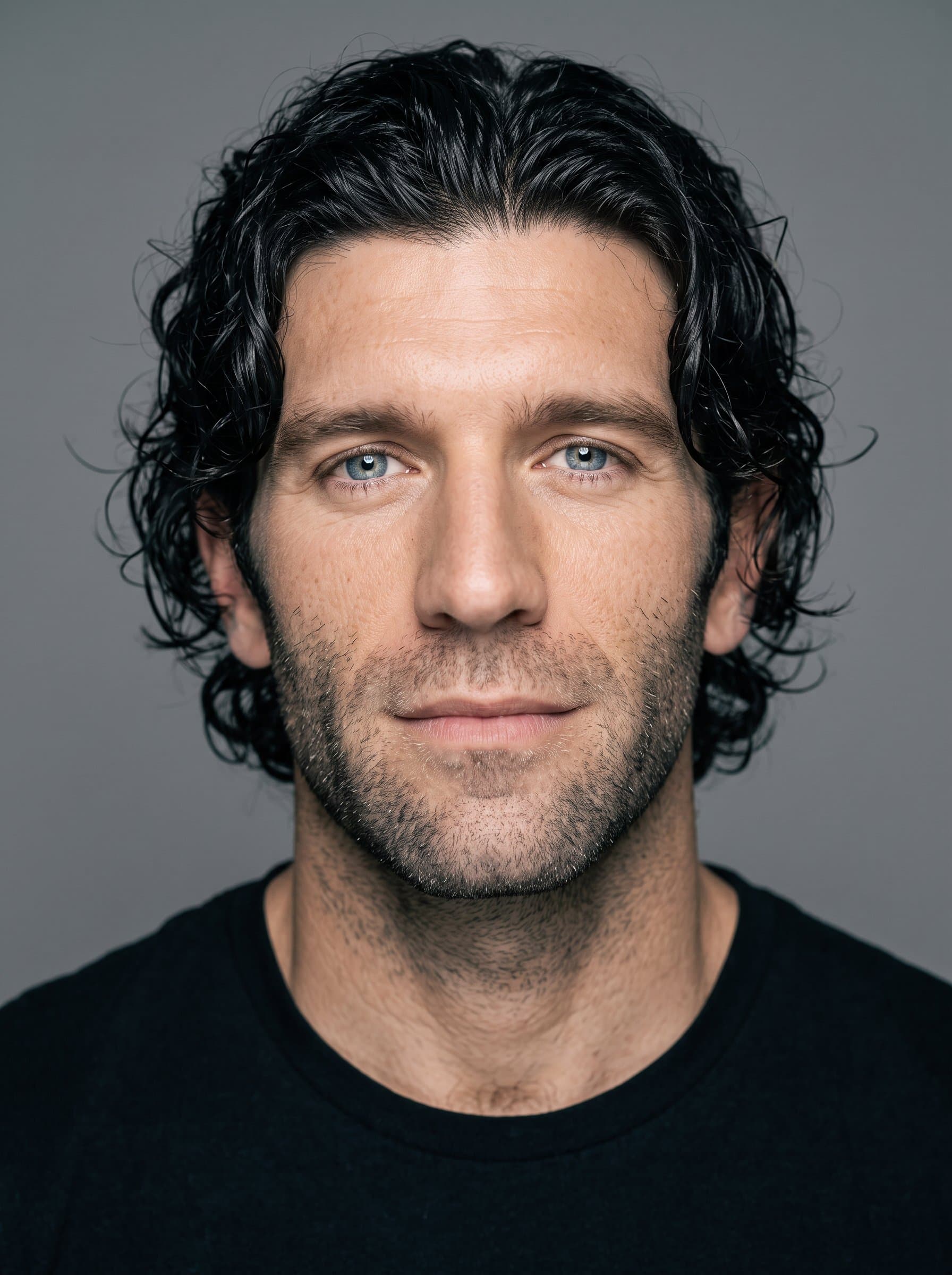 Create a headshot highlighting the man's thoughtful expression and bright eyes. Capture under diffused lighting to even out skin tones, with a seamless background providing a clean, distraction-free composition.