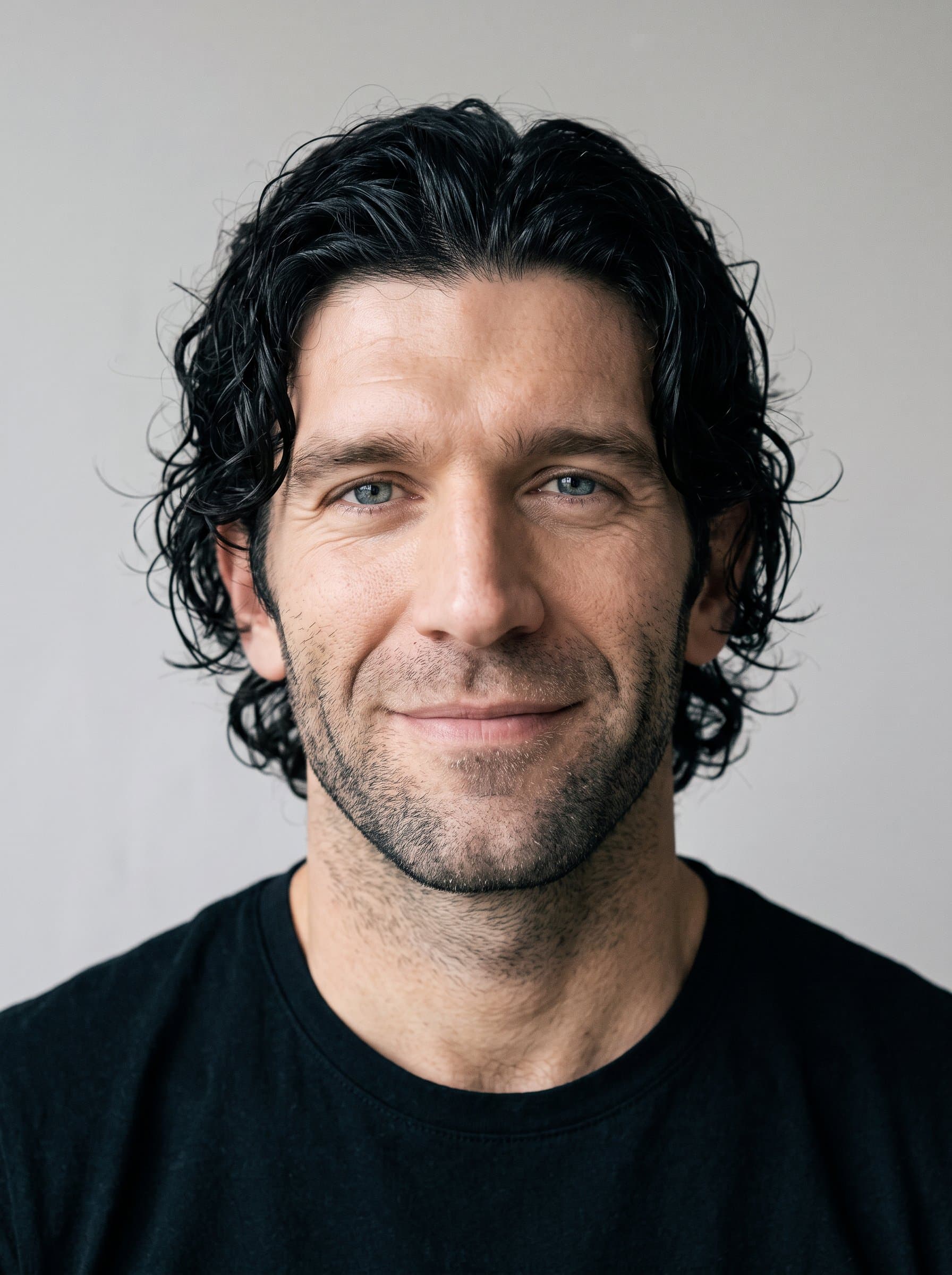 Generate a headshot featuring a gentle expression, with natural light casting soft shadows. Position the man in front of a plain backdrop, ensuring crisp outlines and a focused representation of their persona.
