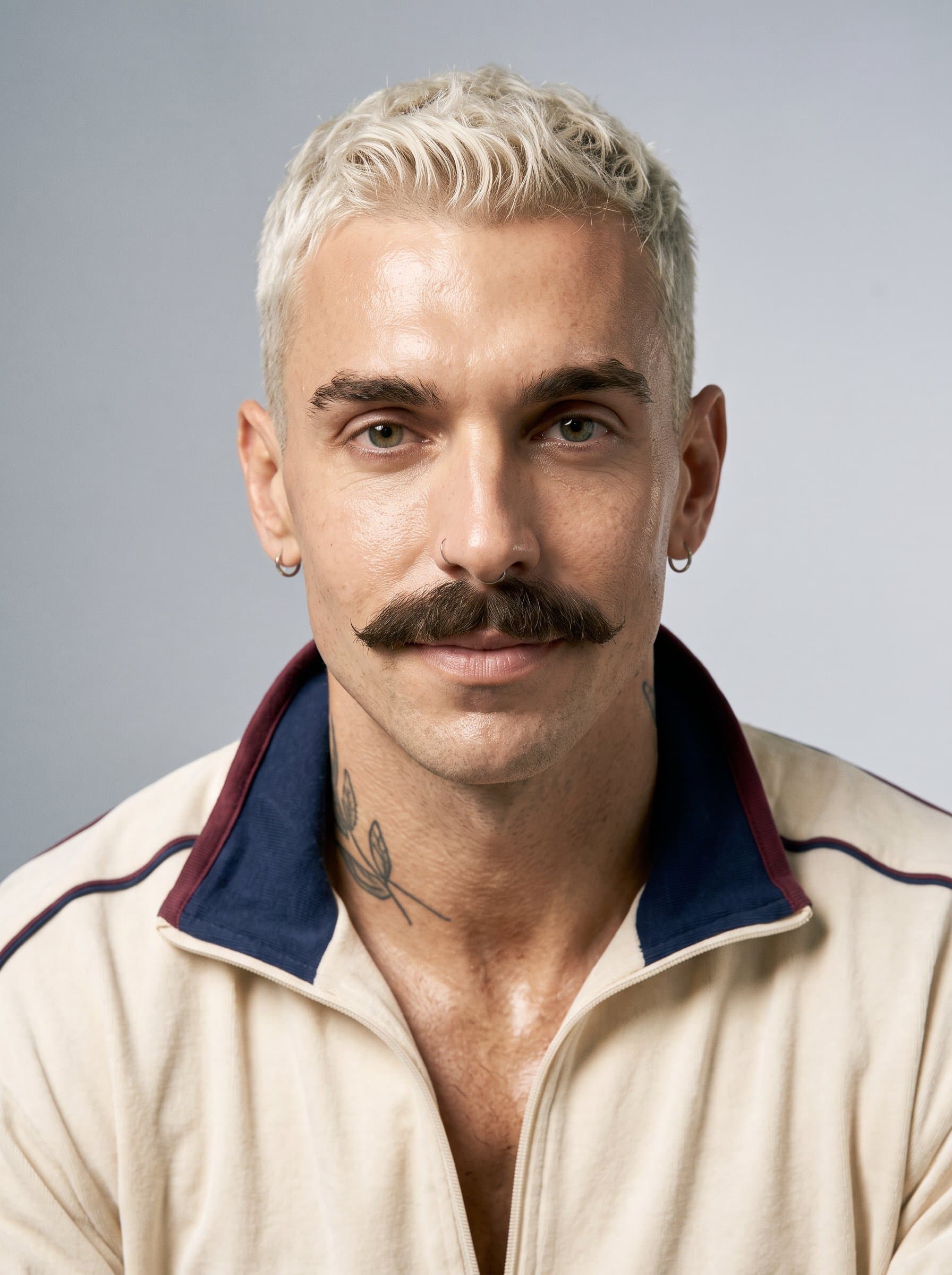 Create a headshot where the man's expression is calm and composed, under soft lighting. A smooth, neutral backdrop provides a professional yet inviting atmosphere, emphasizing the man's confidence.
