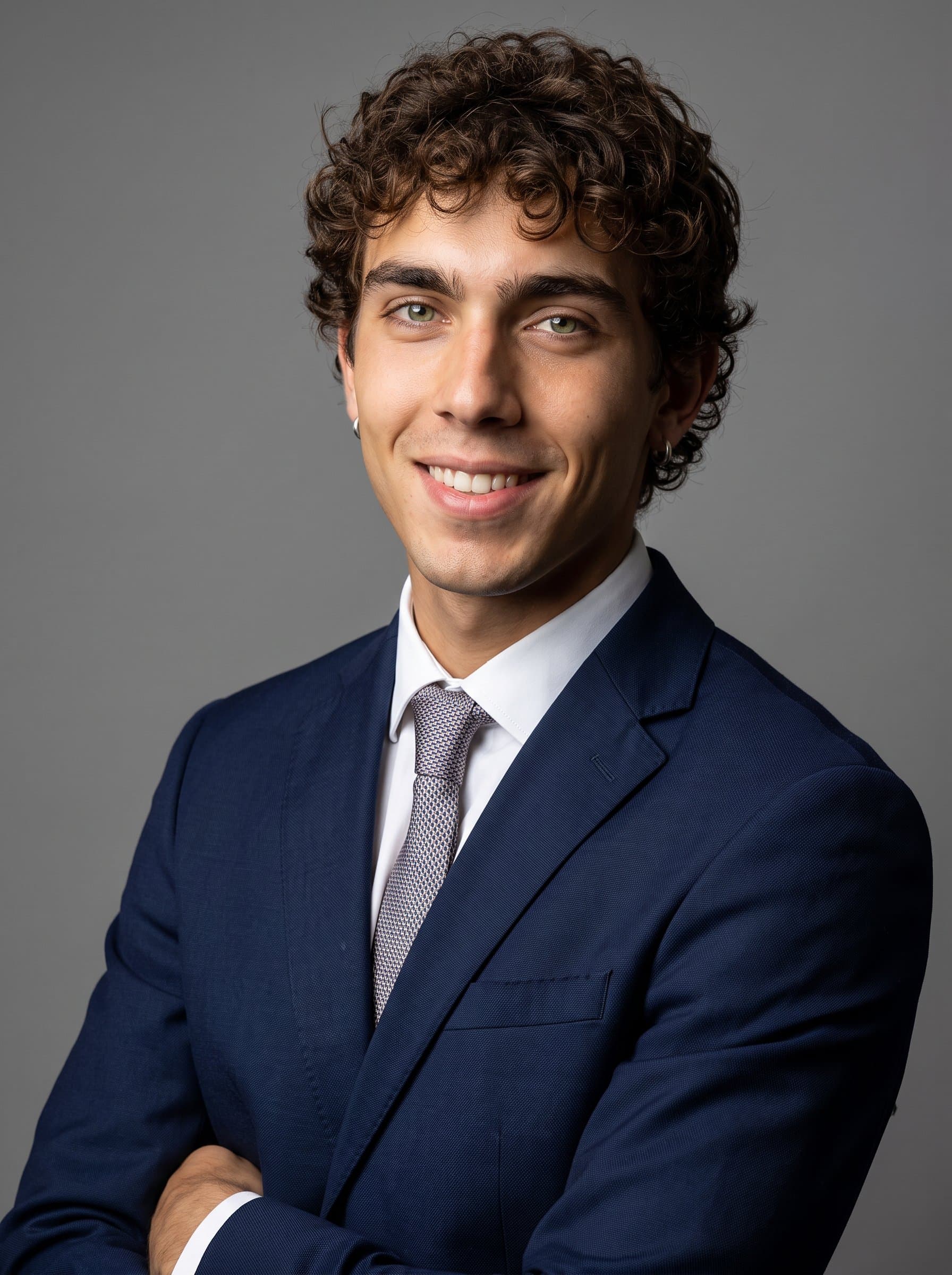 Generate a headshot showcasing a charismatic man with a slight grin and bright eyes. Use a simple, solid-color background and controlled lighting to highlight the personality and professionalism in the portrait.