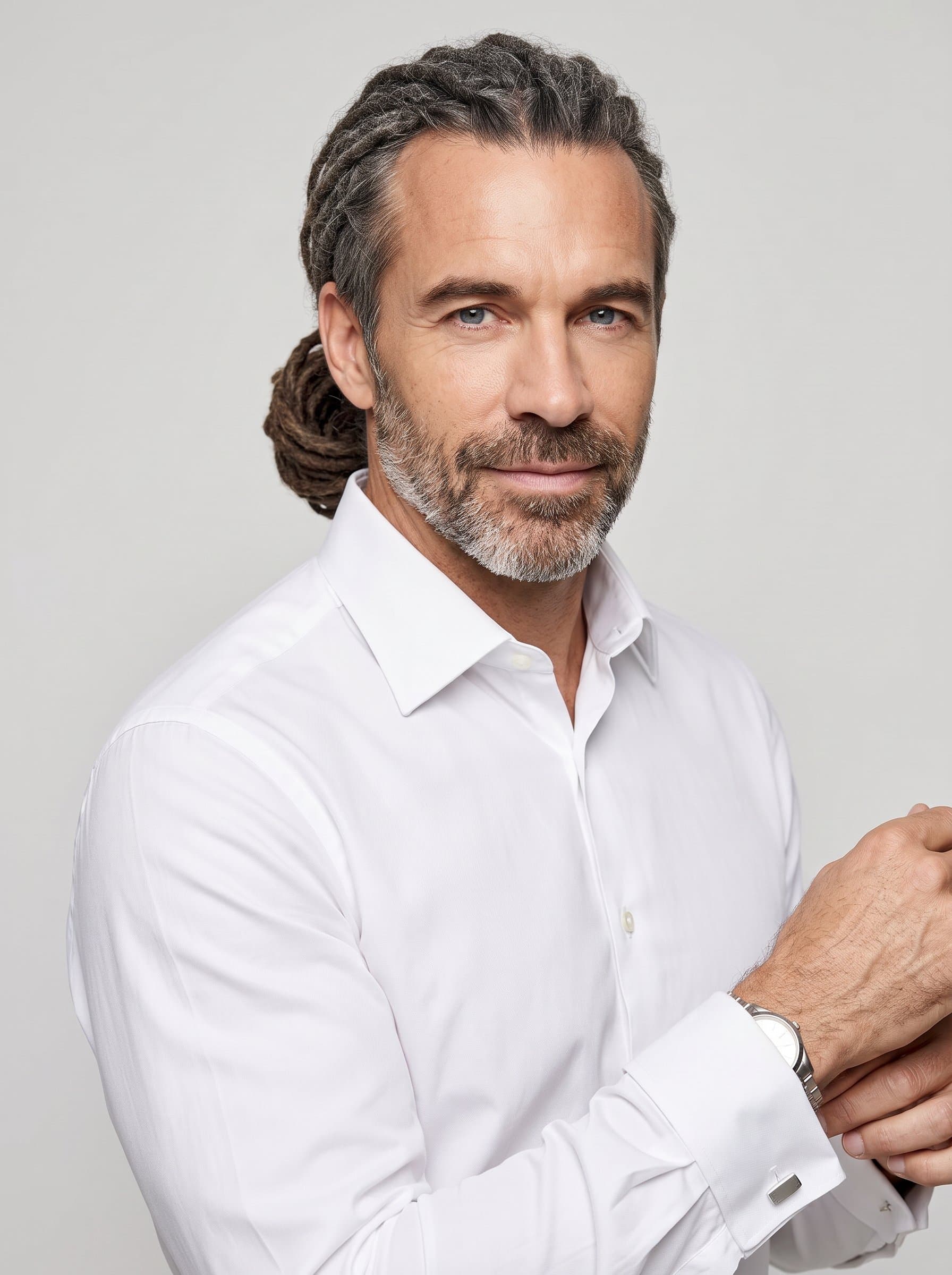 Craft a photorealistic headshot of featuring an man with dreadlocks pulled back, dressed in a formal dress shirt. The setting is a well-lit studio with a neutral backdrop, enhancing their professional demeanor.