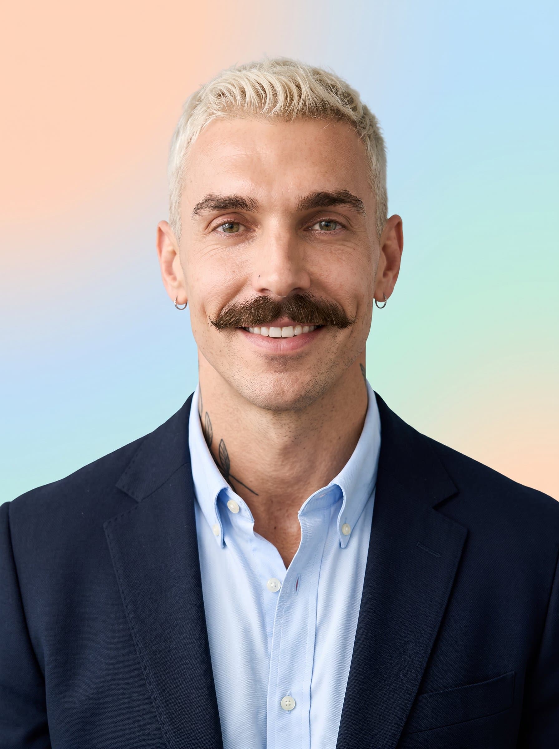 : Design a headshot with a soft, pastel gradient background. The man's expression is gentle and approachable, wearing smart casual attire, creating a calming and friendly social media presence.