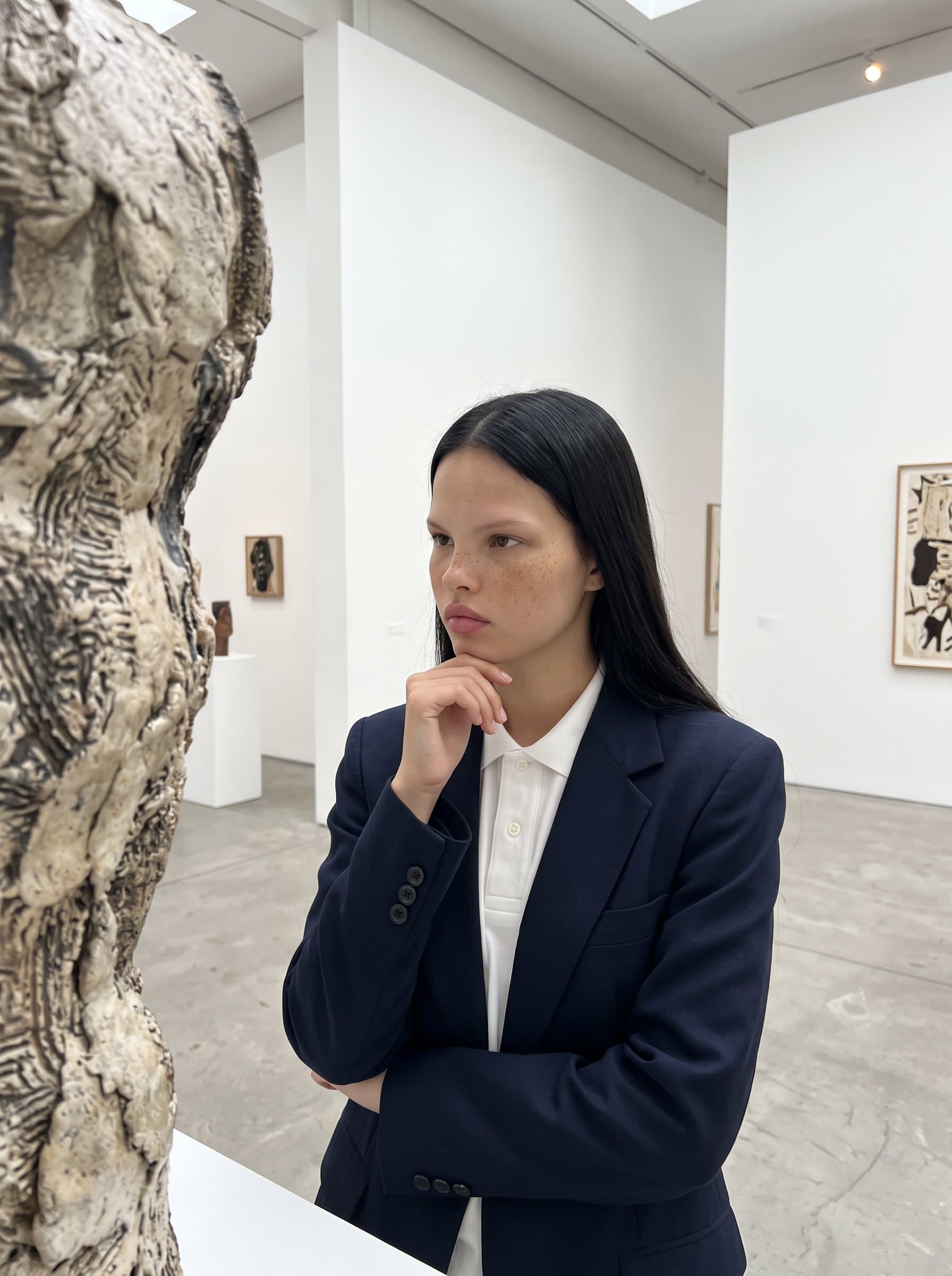 Against the backdrop of a minimalist art gallery, dressed in smart-casual attire, contemplating a piece of art, reflecting an appreciation for creativity and a keen eye for detail.