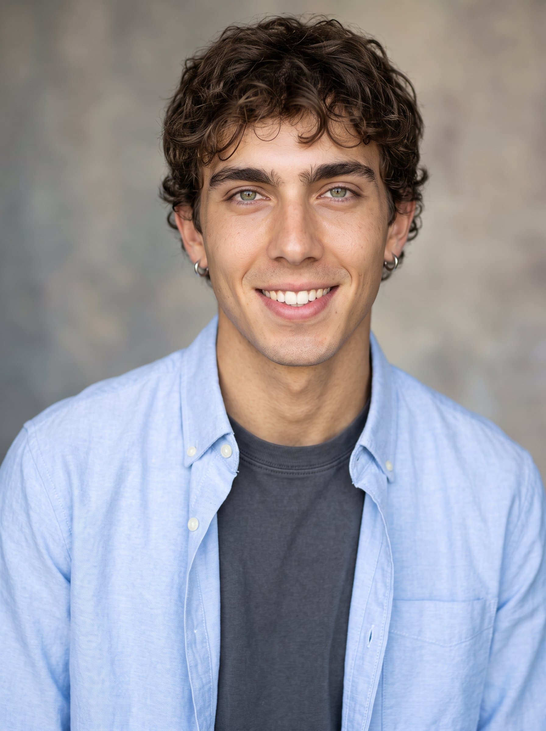 Produce 's headshot, showcasing them in a relaxed business look with a stylish shirt, set against a neutral backdrop interplaying soft gray and beige hues, illuminated by gentle lighting.