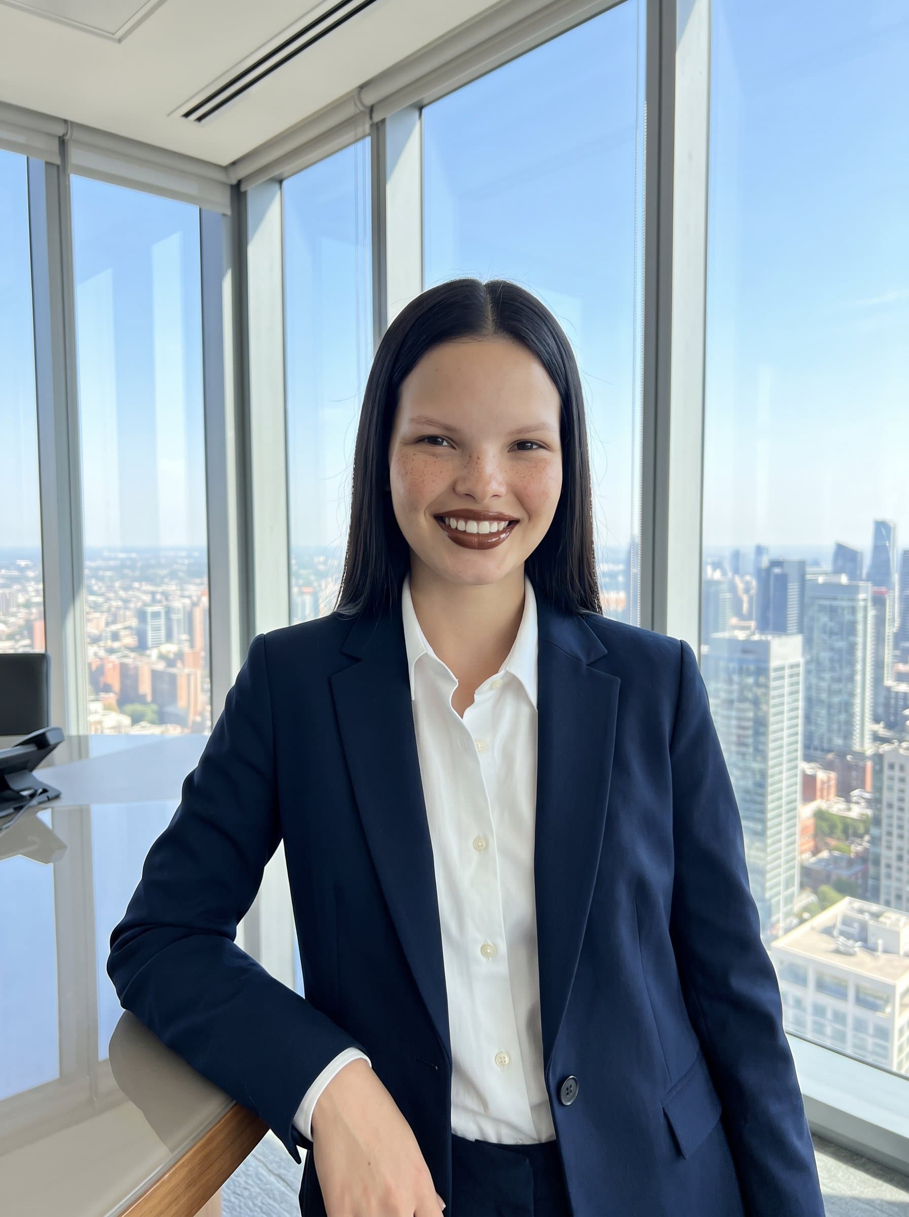 Generate a captured in a high-rise office with a city view. The attire is sharp and formal, while the expression is confident and engaging, perfect for executive-level positions.